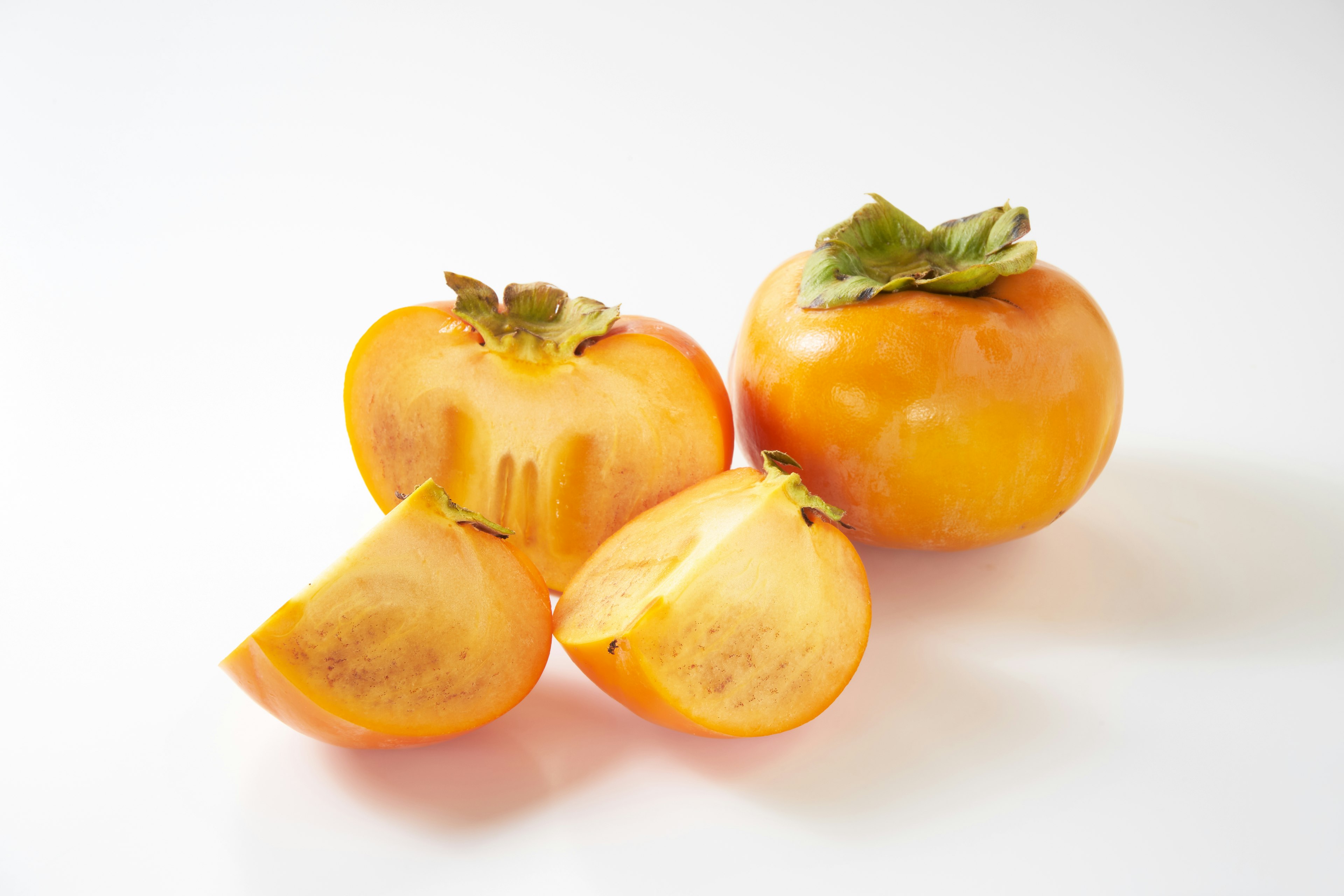 Sliced persimmons showcasing vibrant orange color with green leaves