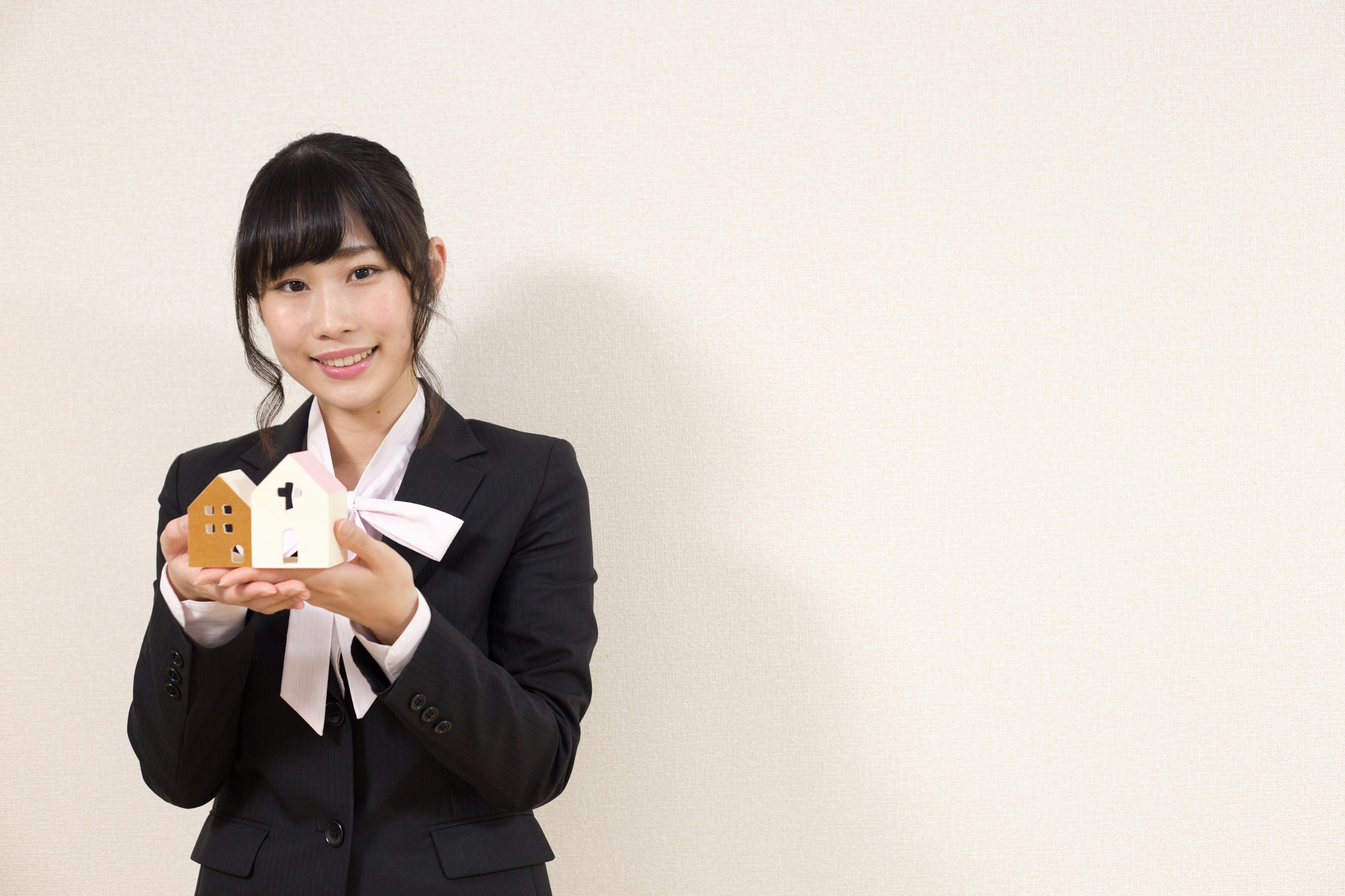 A woman in a suit holding cookie-shaped sweets and smiling