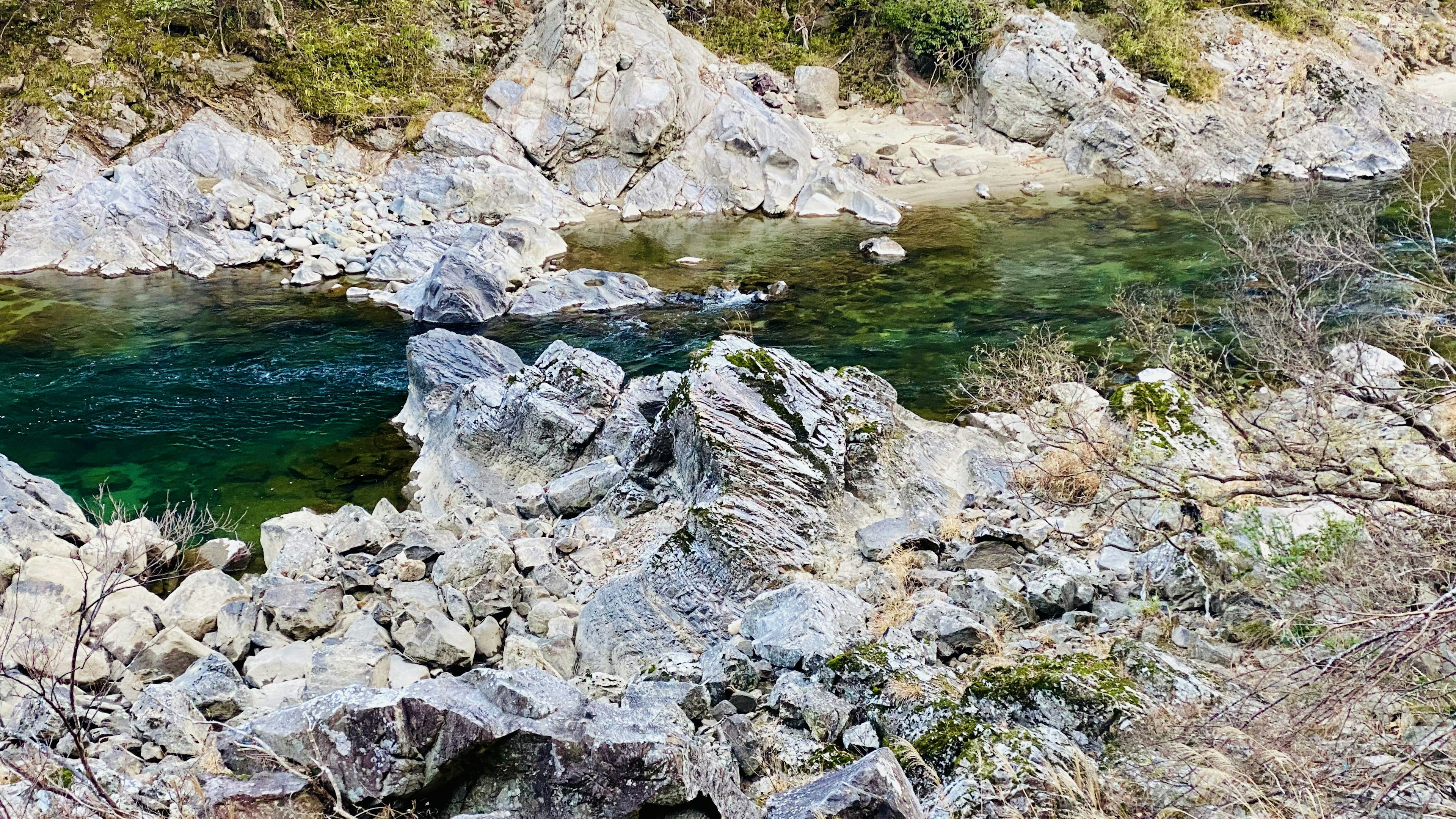 Malersicher Blick auf einen Bach mit grünem Wasser und felsigem Gelände