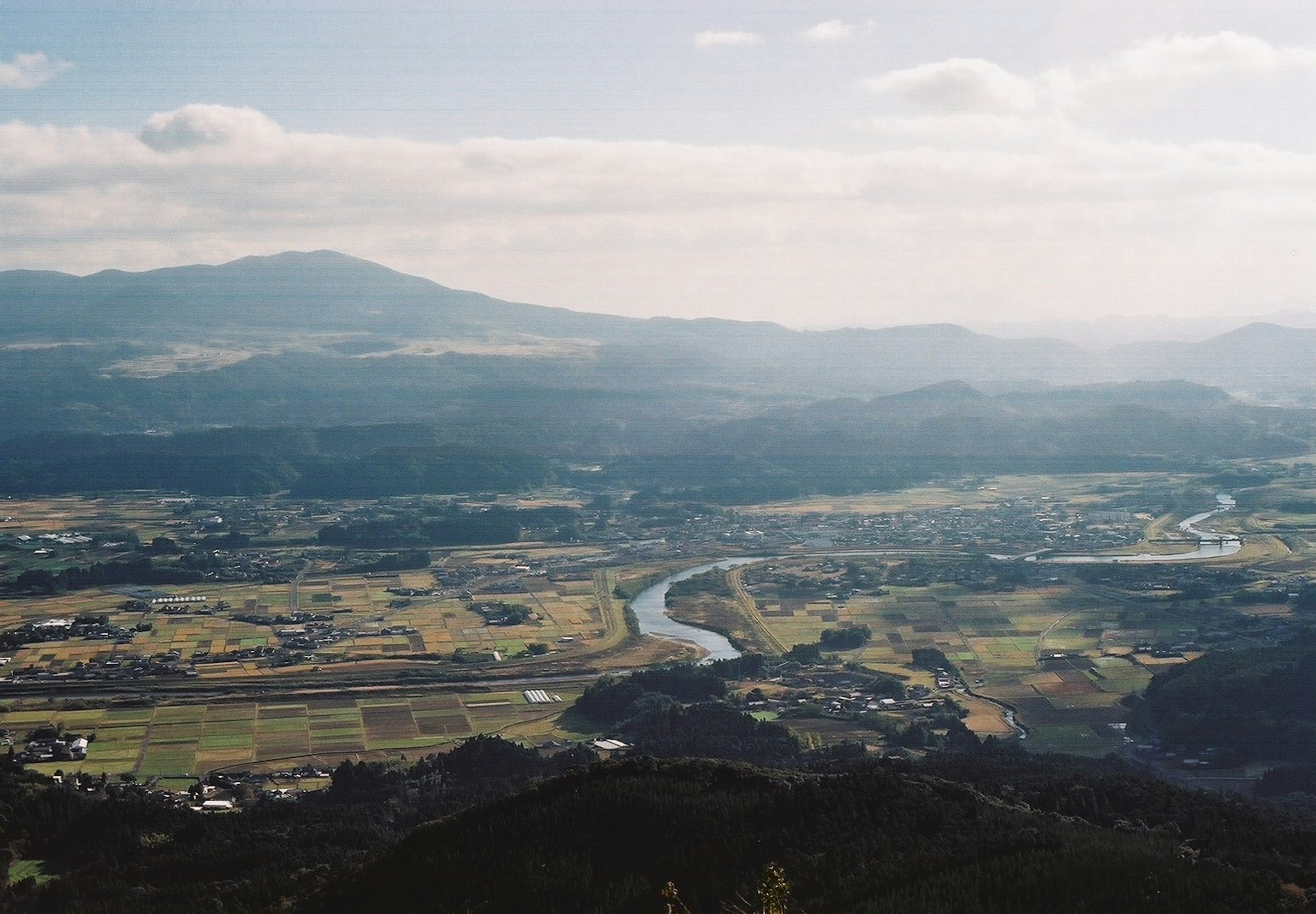 Vista escénica desde una montaña sobre tierras de cultivo y un río