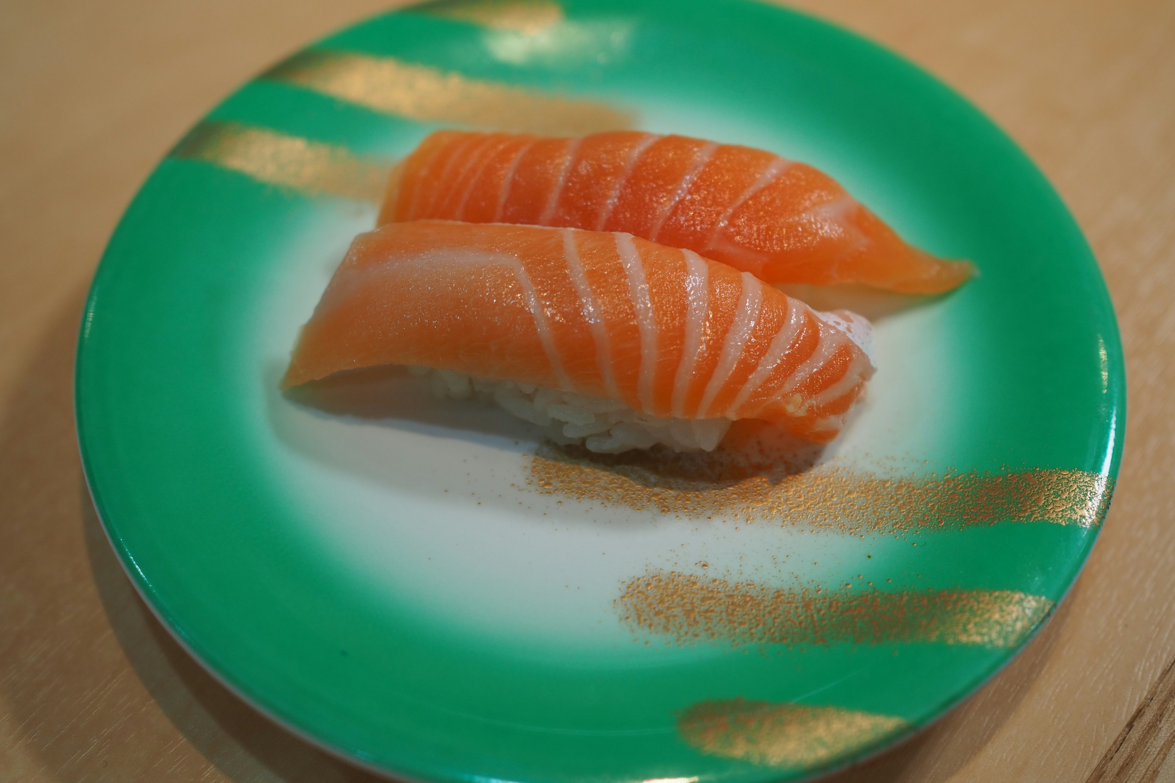 Sushi salmon di atas piring hijau