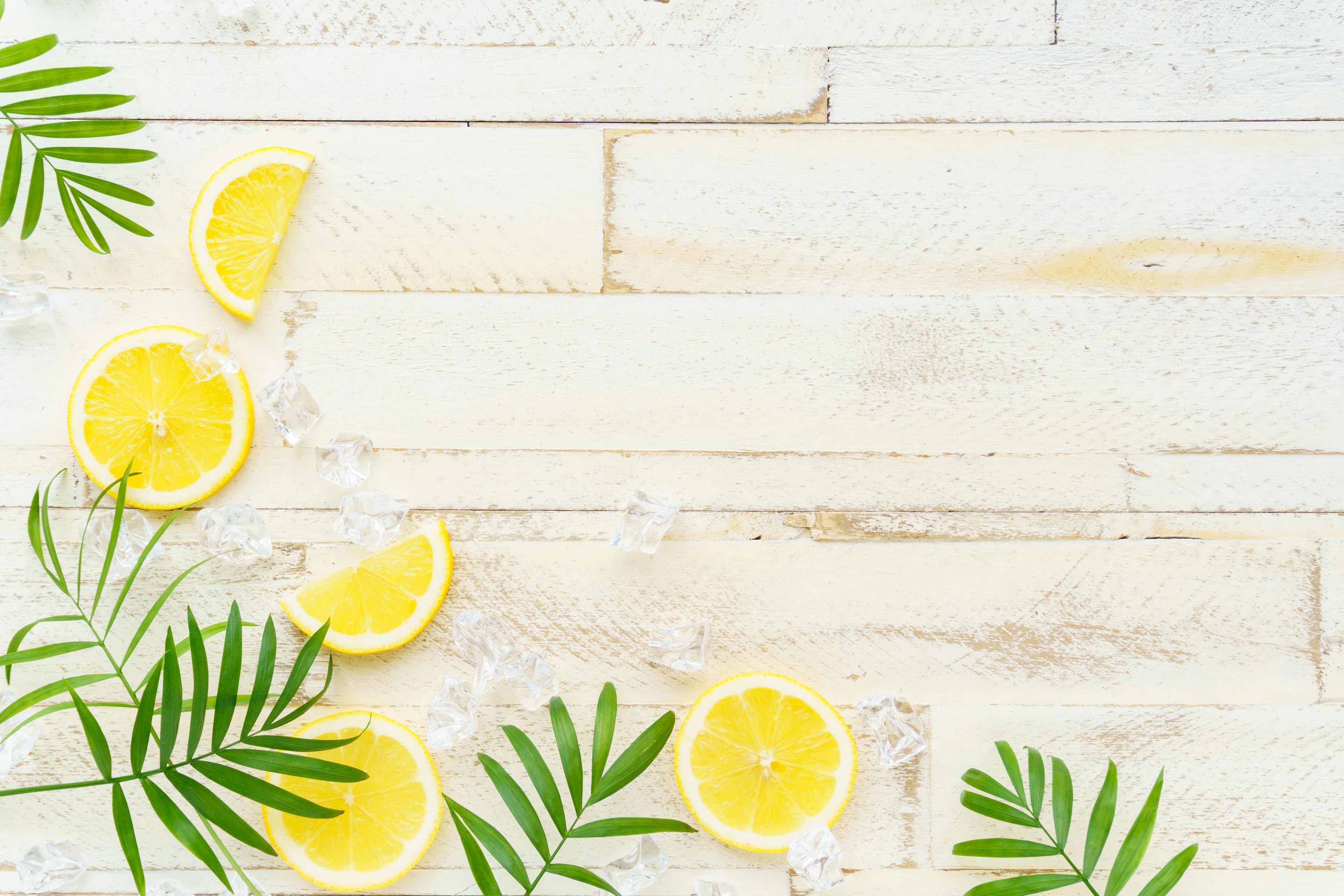 Slices of lemon and green leaves arranged on a wooden table