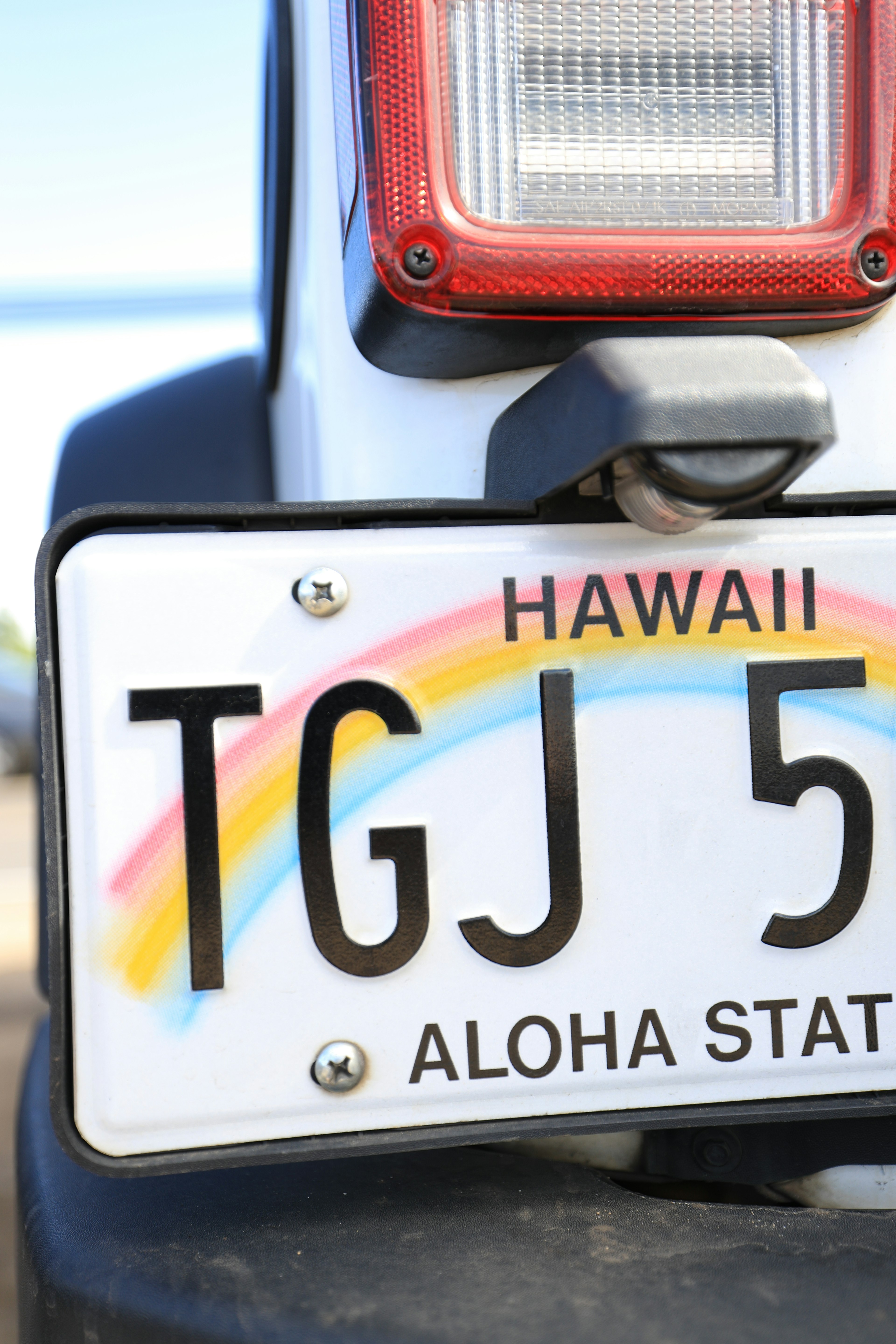 Plaque d'immatriculation d'Hawaï TGJ 5 avec motif arc-en-ciel près d'un feu arrière de véhicule