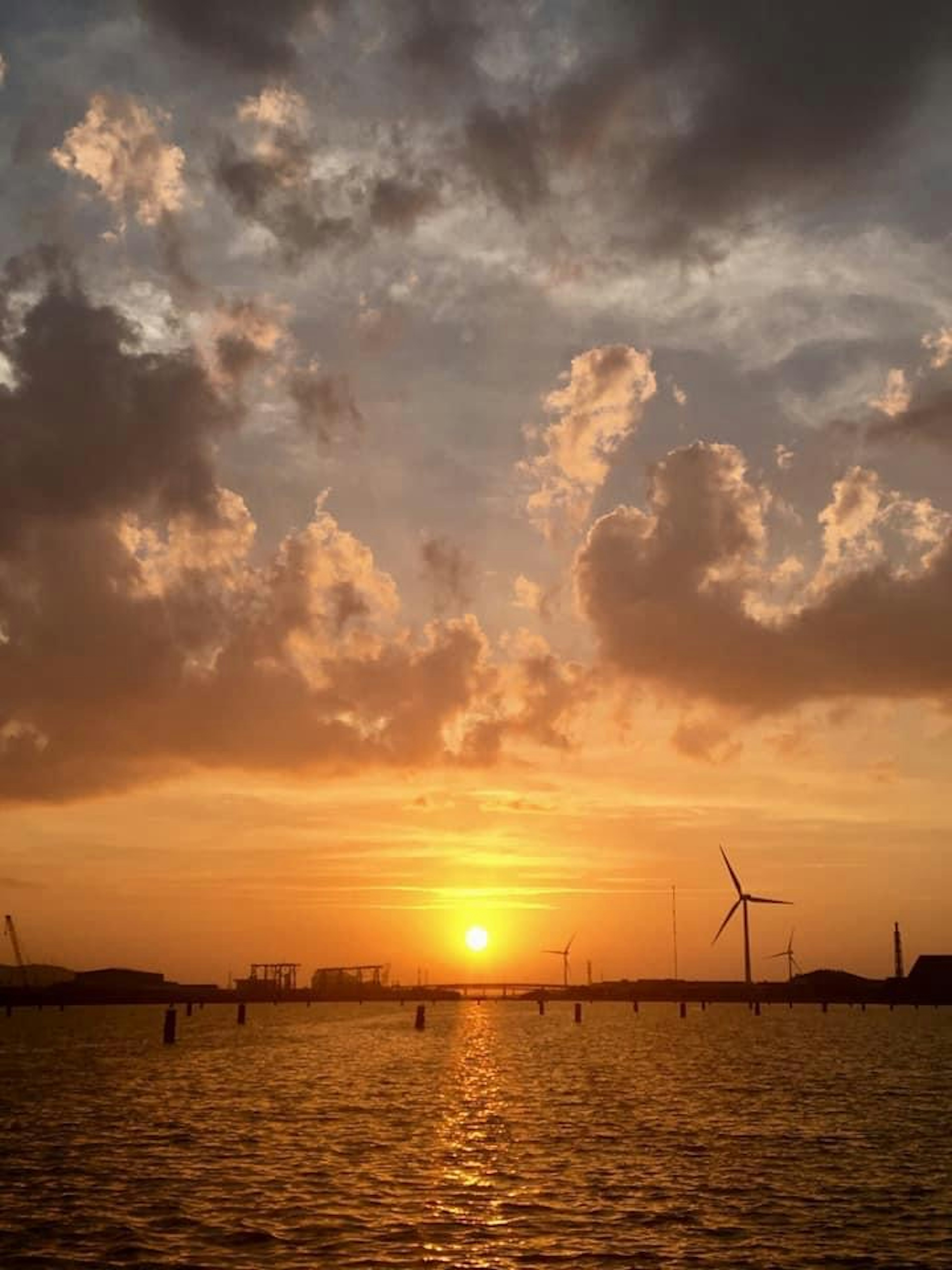 夕日が海に沈む風景と風車が見える壮大な空