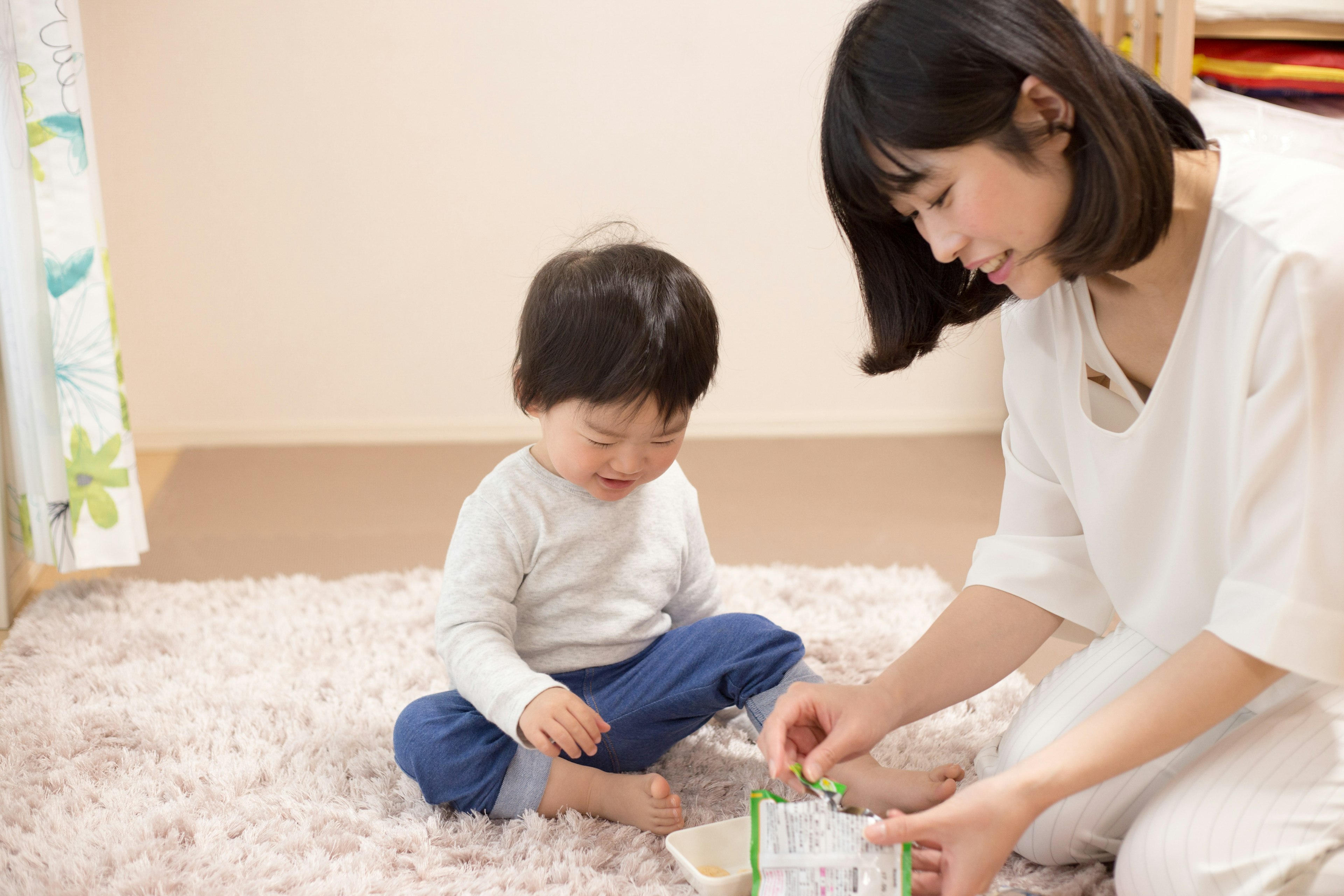 Warm moment of a mother playing with a toddler on a soft rug