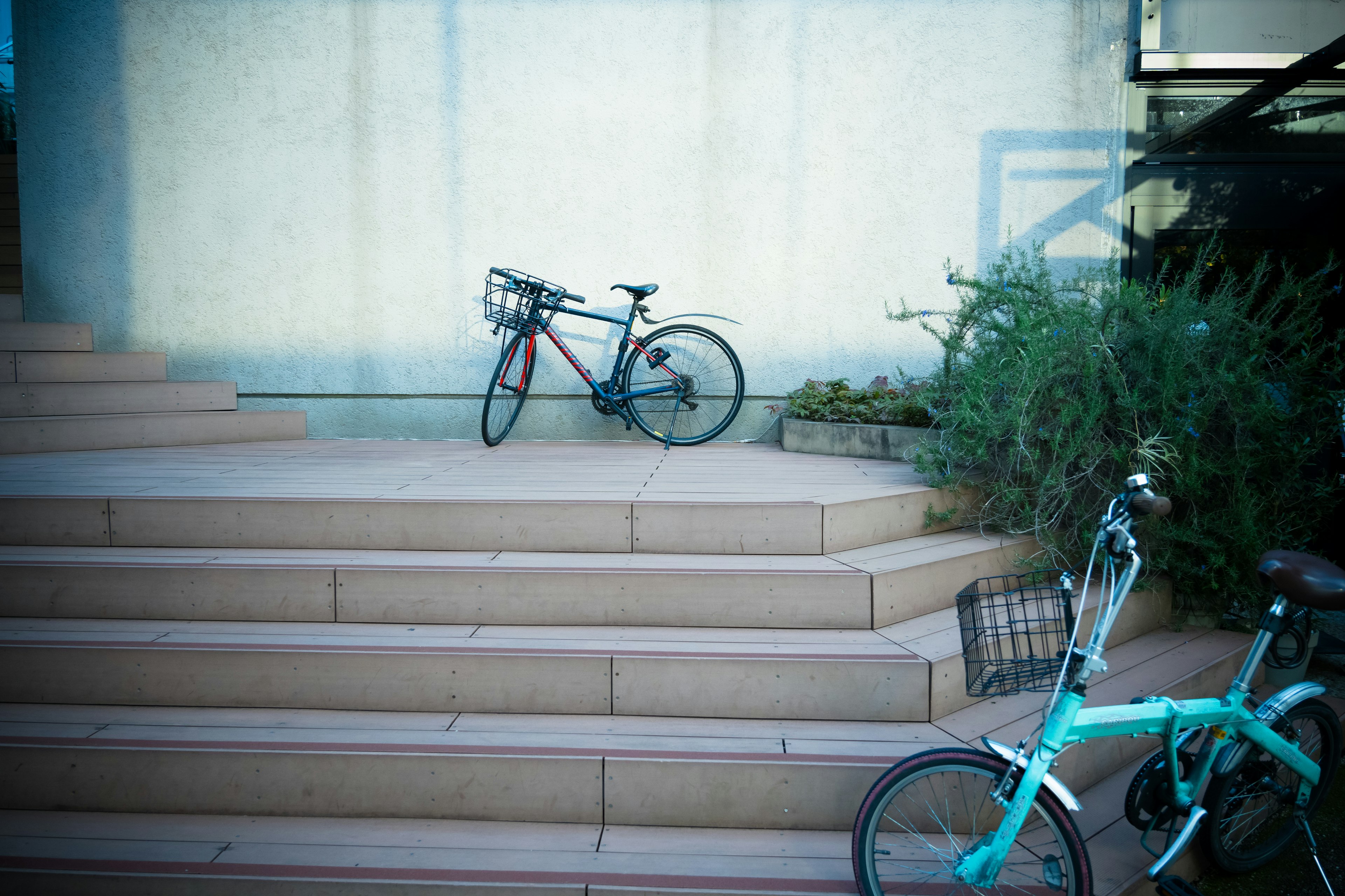 Two bicycles resting on stairs with greenery in the background