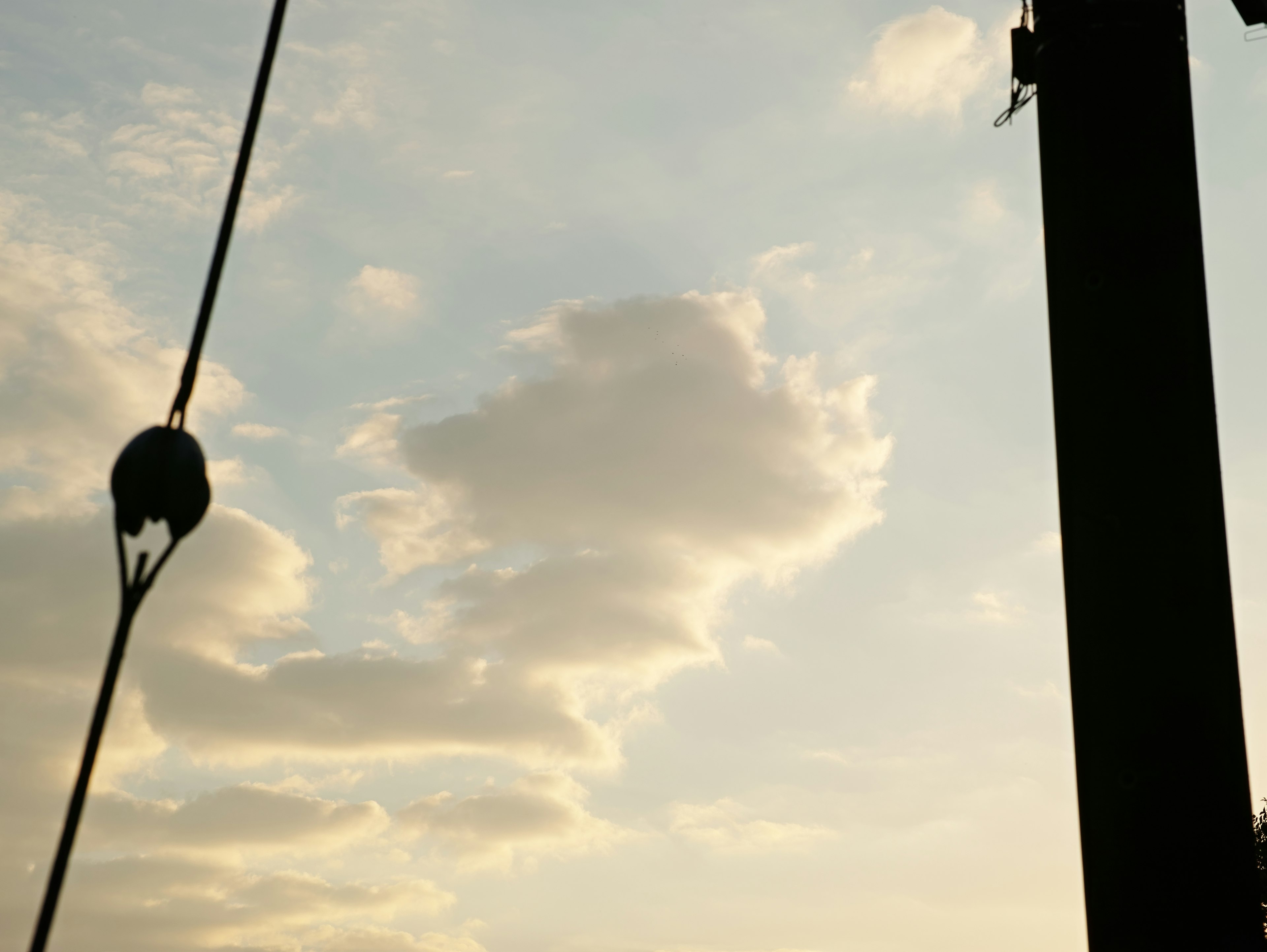 Silhouette d'un poteau électrique contre un ciel de coucher de soleil avec des nuages