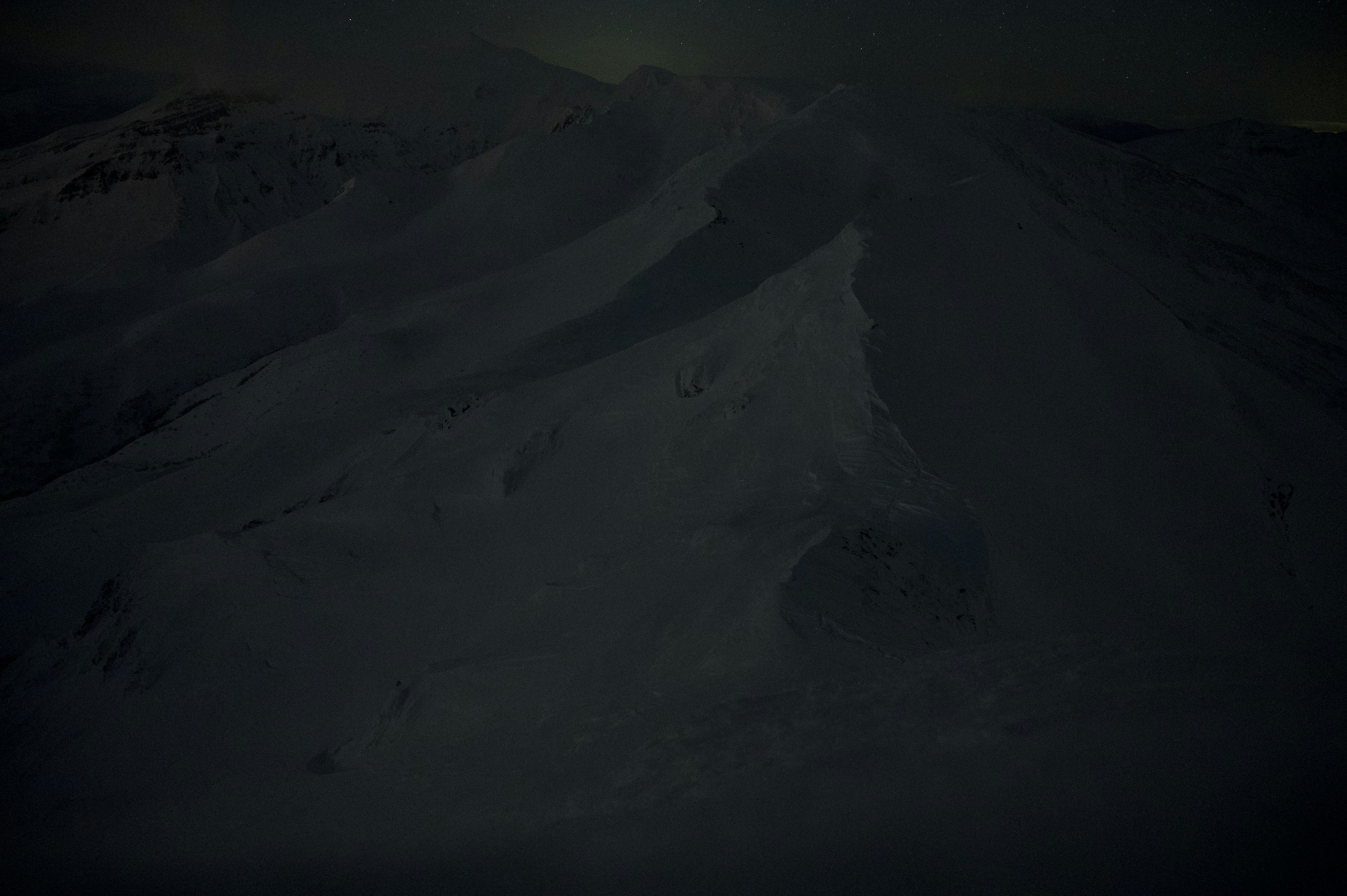 Paesaggio montano innevato scuro con neve bianca e contorni di montagna visibili