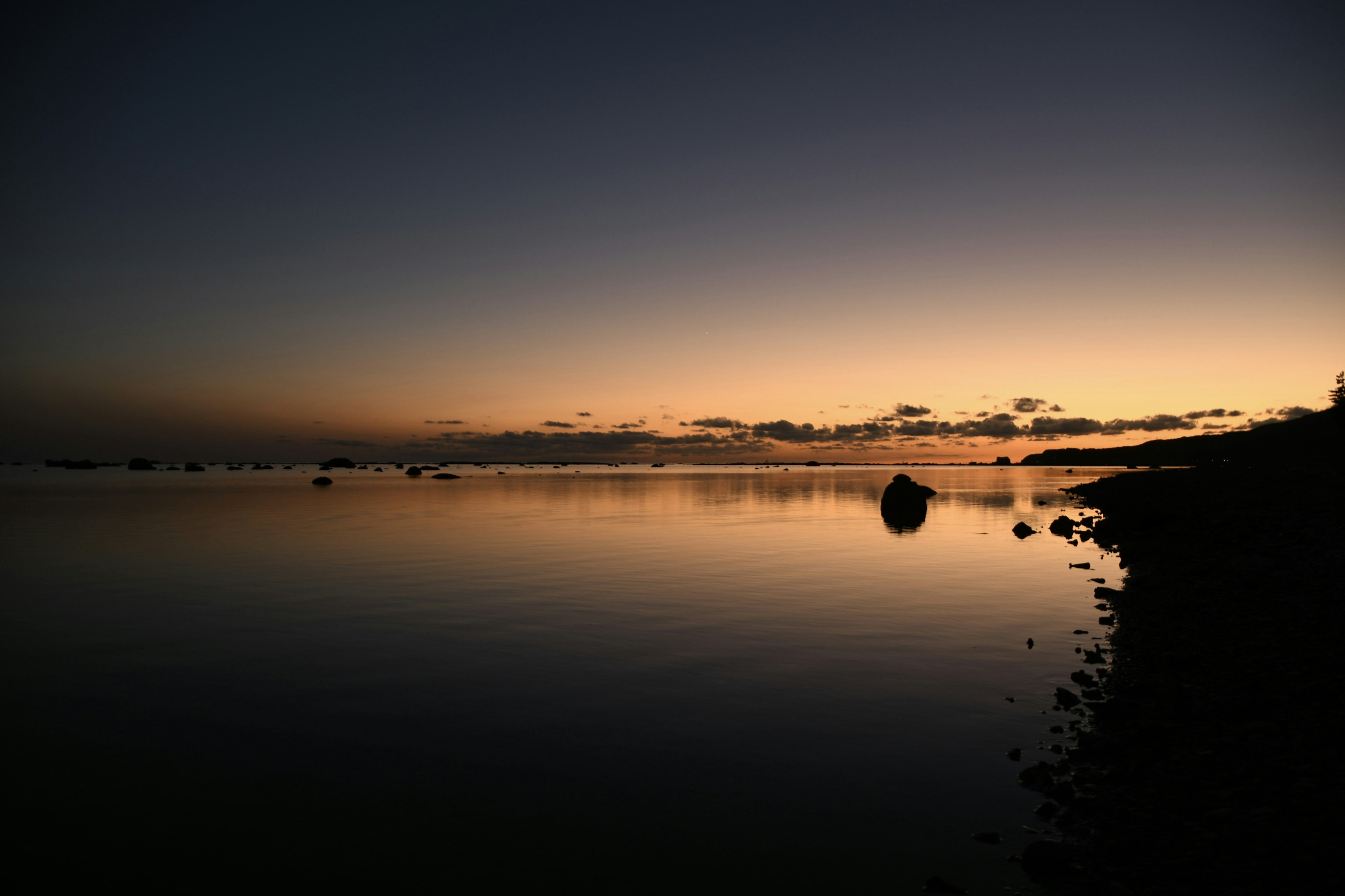 Paesaggio marittimo calmo al tramonto con una superficie d'acqua tranquilla