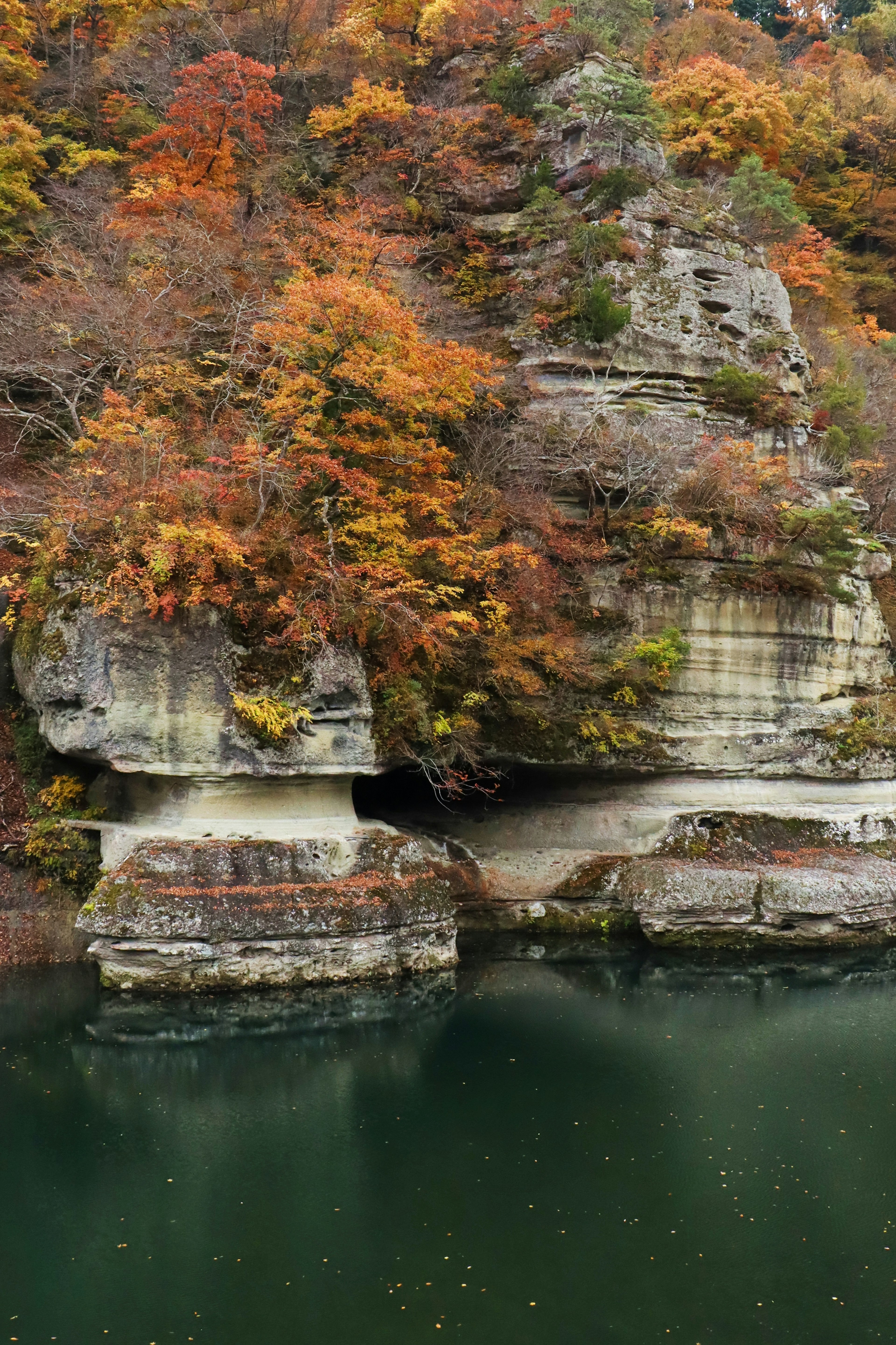 Vista panoramica di una scogliera rocciosa circondata da fogliame autunnale colorato e un lago tranquillo