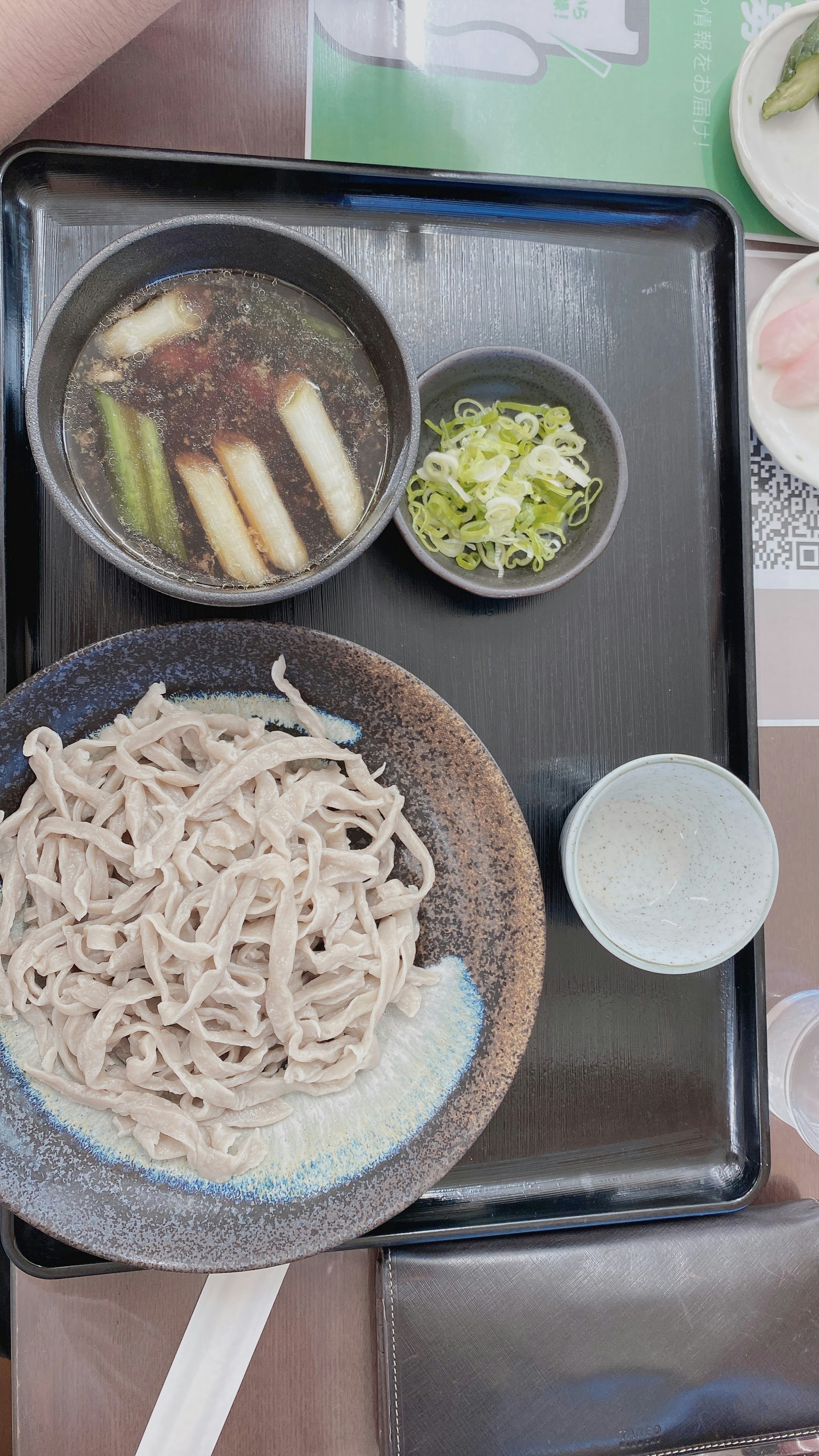 A Japanese meal featuring soba noodles, soup with vegetables, and garnishes