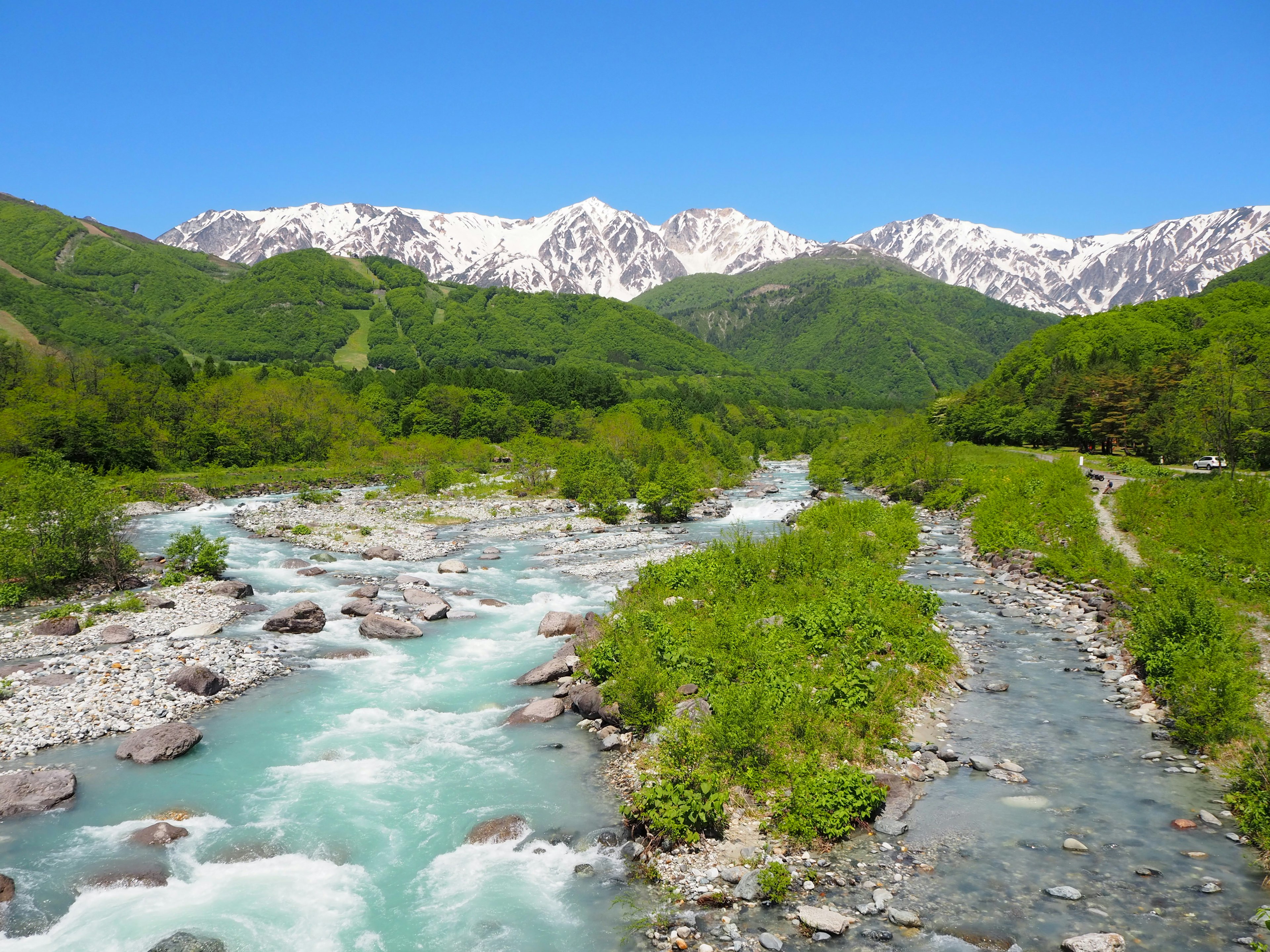 Ruisseaux clairs coulant sur fond de montagnes verdoyantes et de sommets enneigés