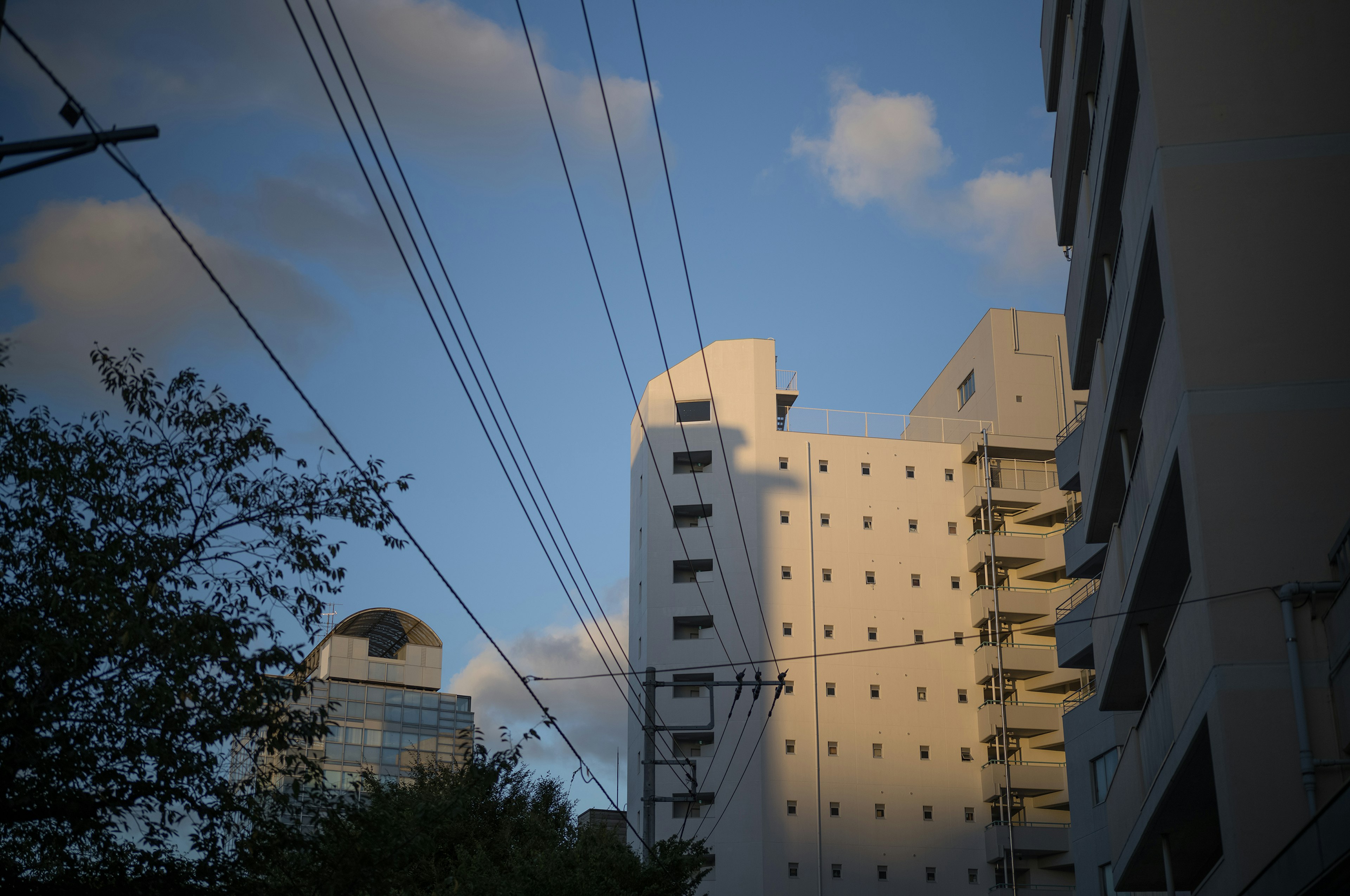 Paisaje urbano con edificios y líneas eléctricas bajo un cielo azul con nubes