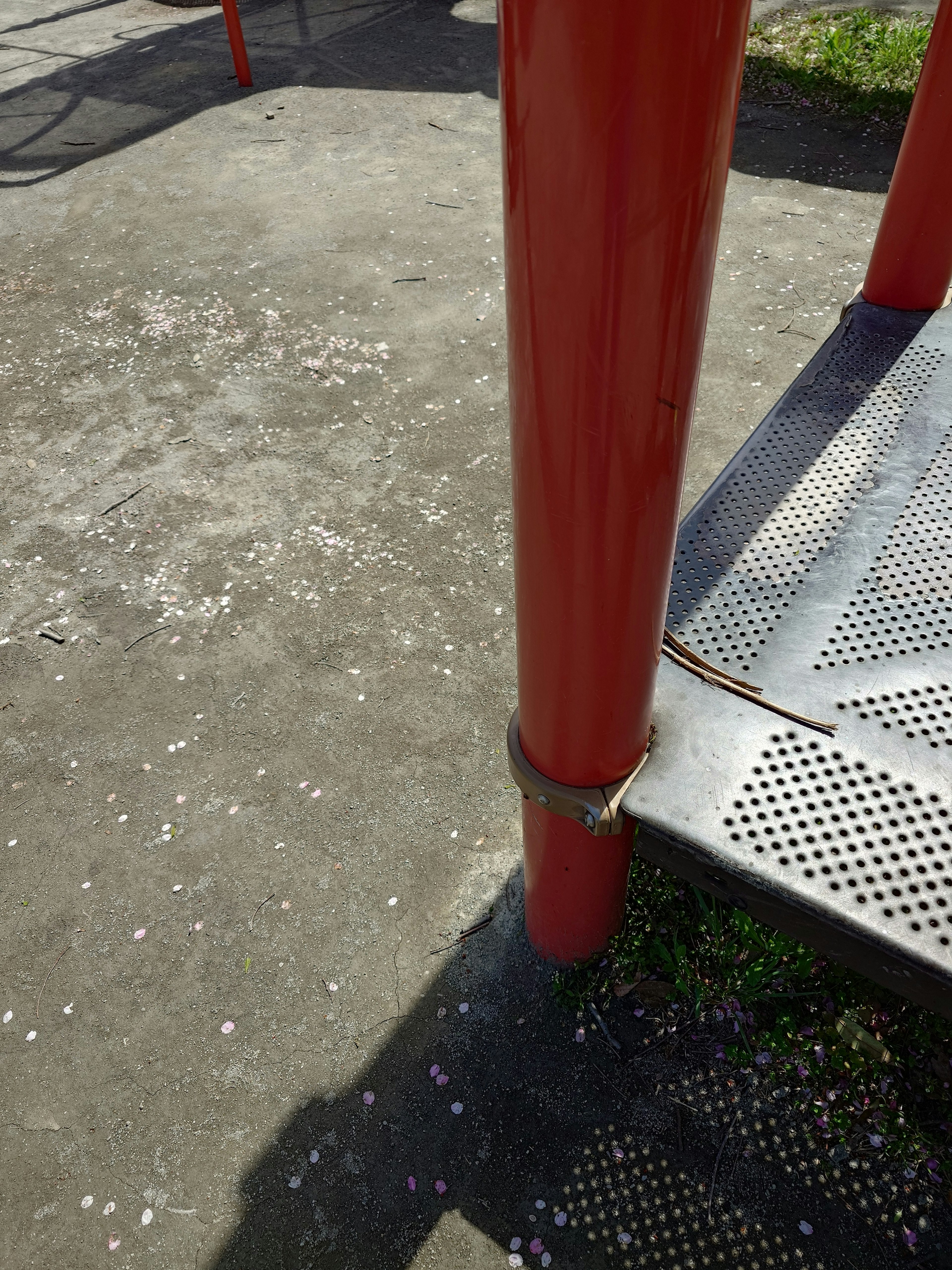 Part of a playground structure featuring a red pole and metal steps