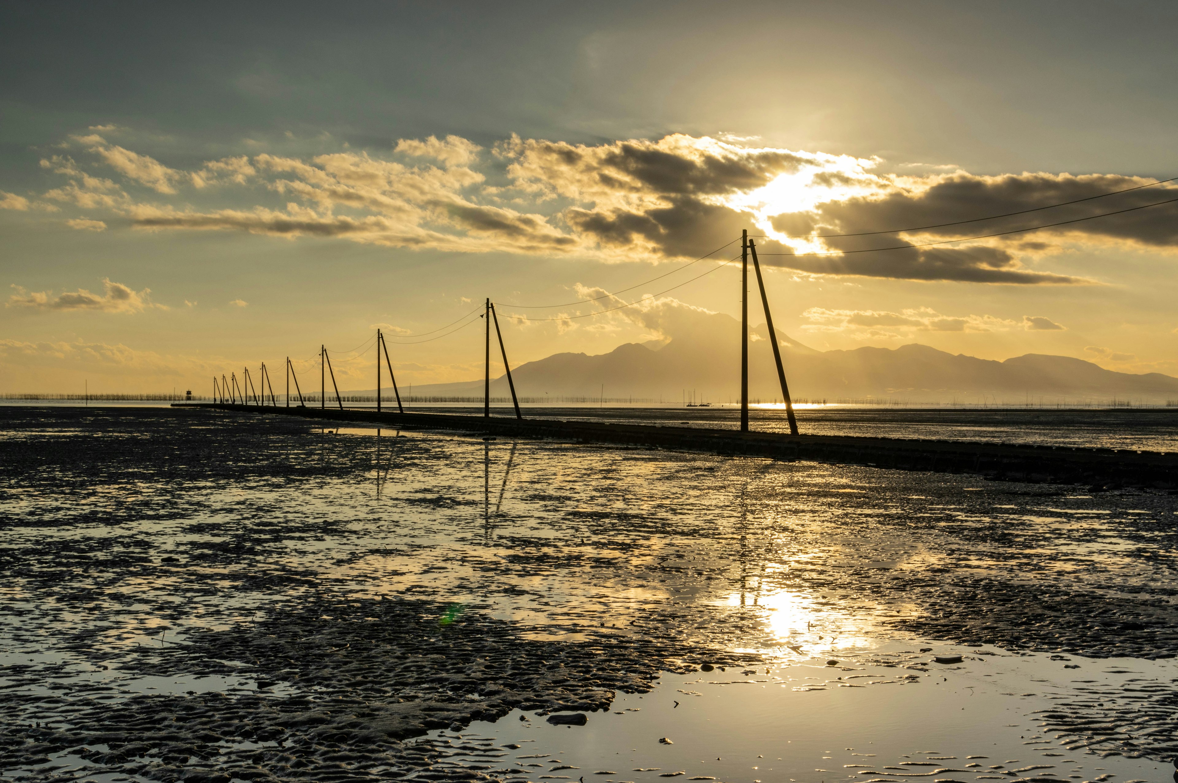 Rangée de poteaux électriques le long d'une côte au coucher du soleil