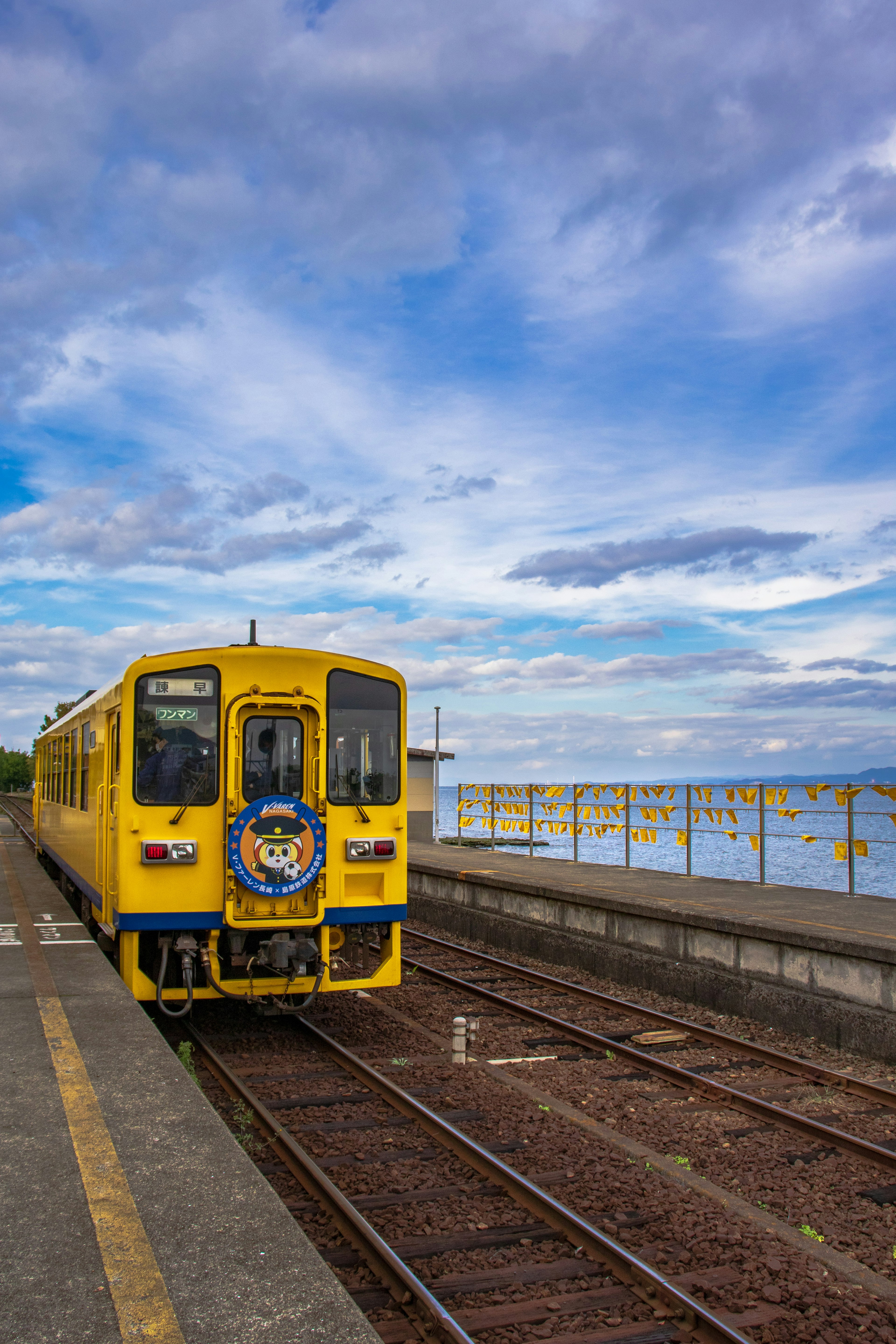 Kereta kuning di stasiun dengan langit biru dan awan di latar belakang