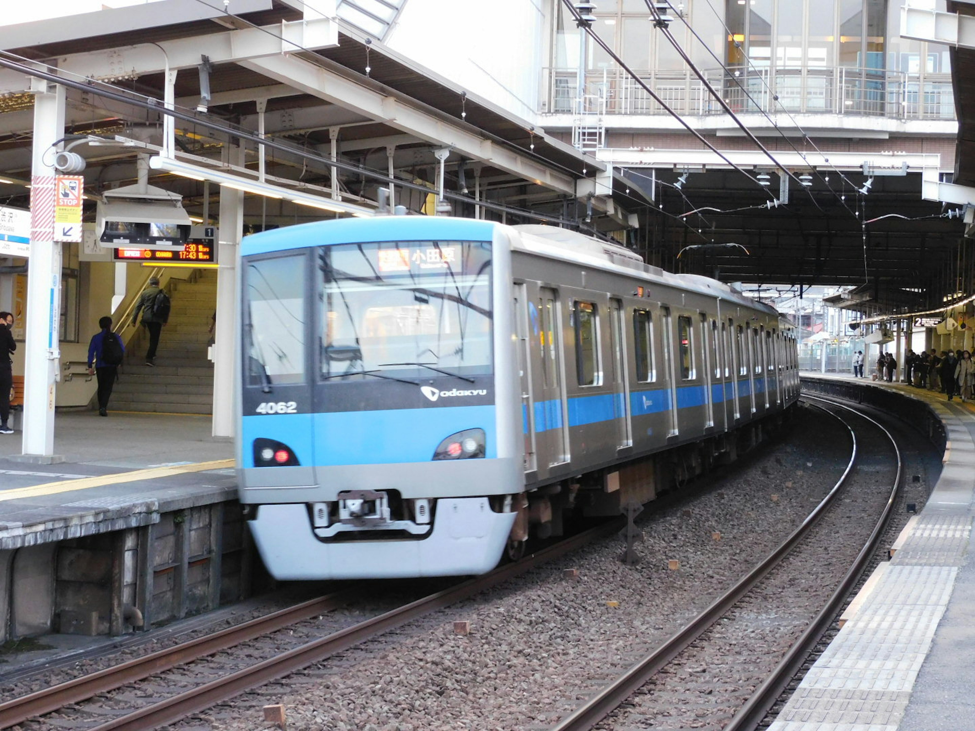 Un train bleu arrivant à une station avec des voies et un quai visibles