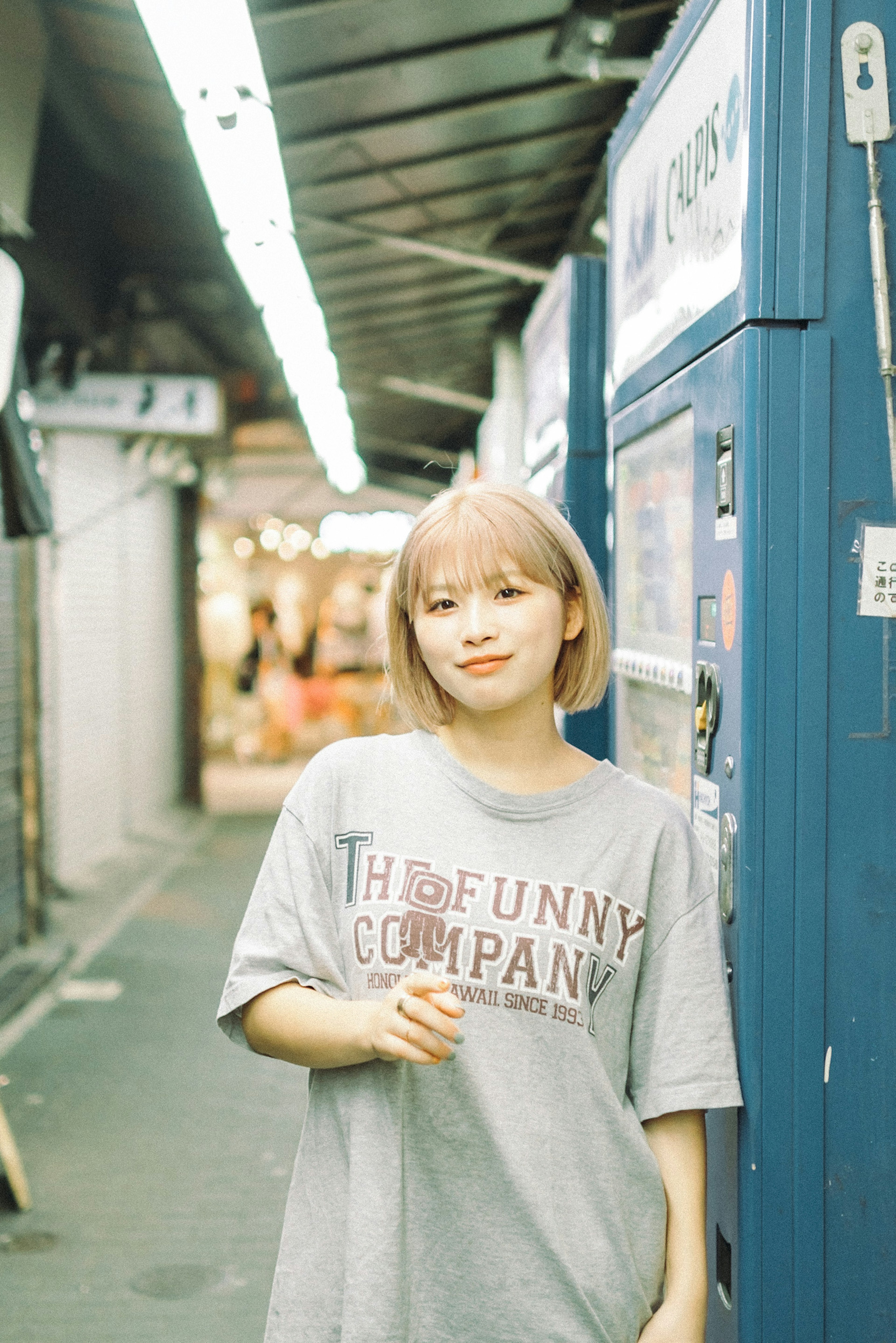 路地に立つ若い女性のポートレート 髪型はボブでグレーのTシャツを着用