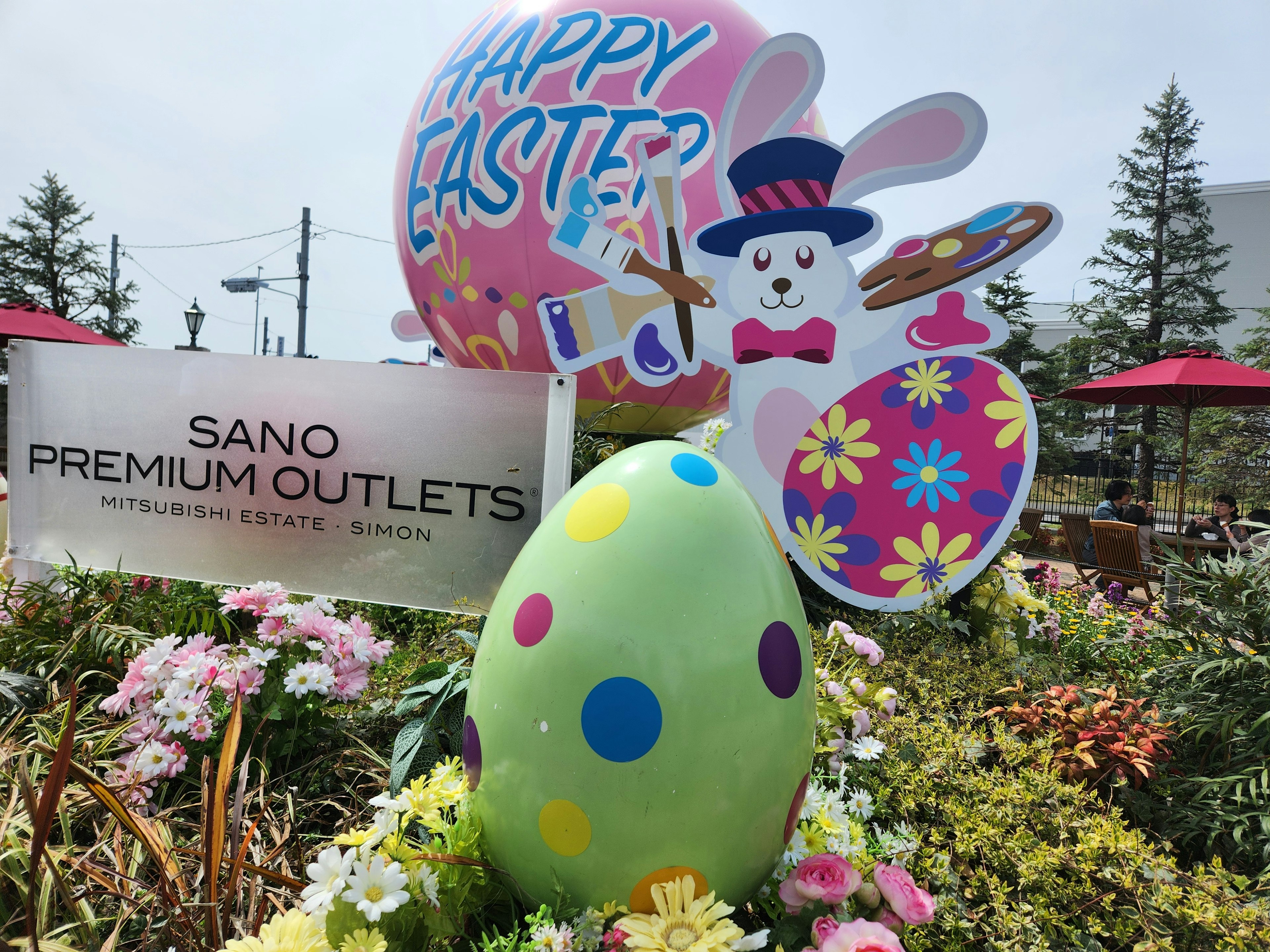 Decoraciones de Pascua coloridas que incluyen un gran globo y un huevo pintado en un jardín de flores