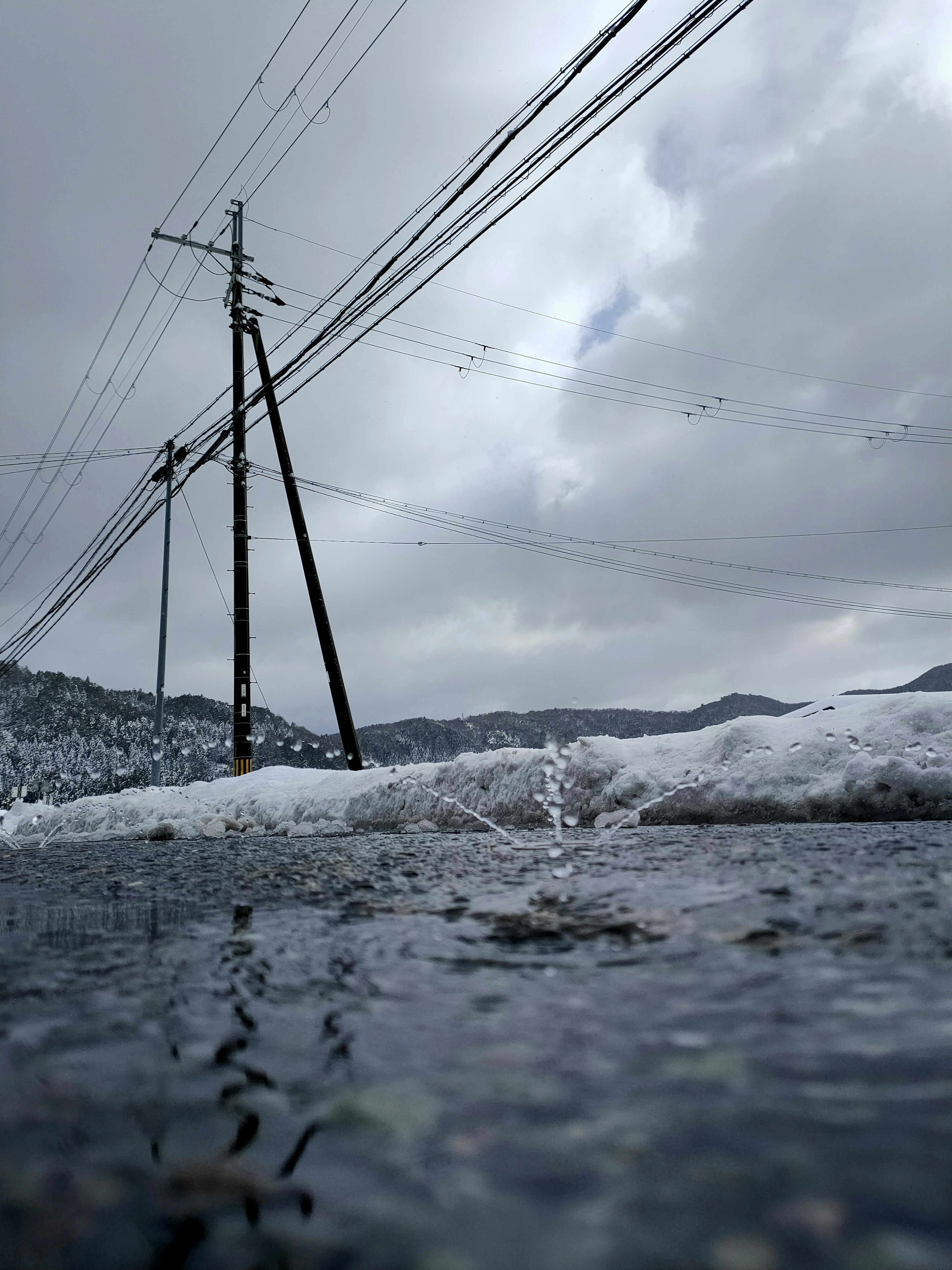 Snow-covered road with power poles and cloudy sky