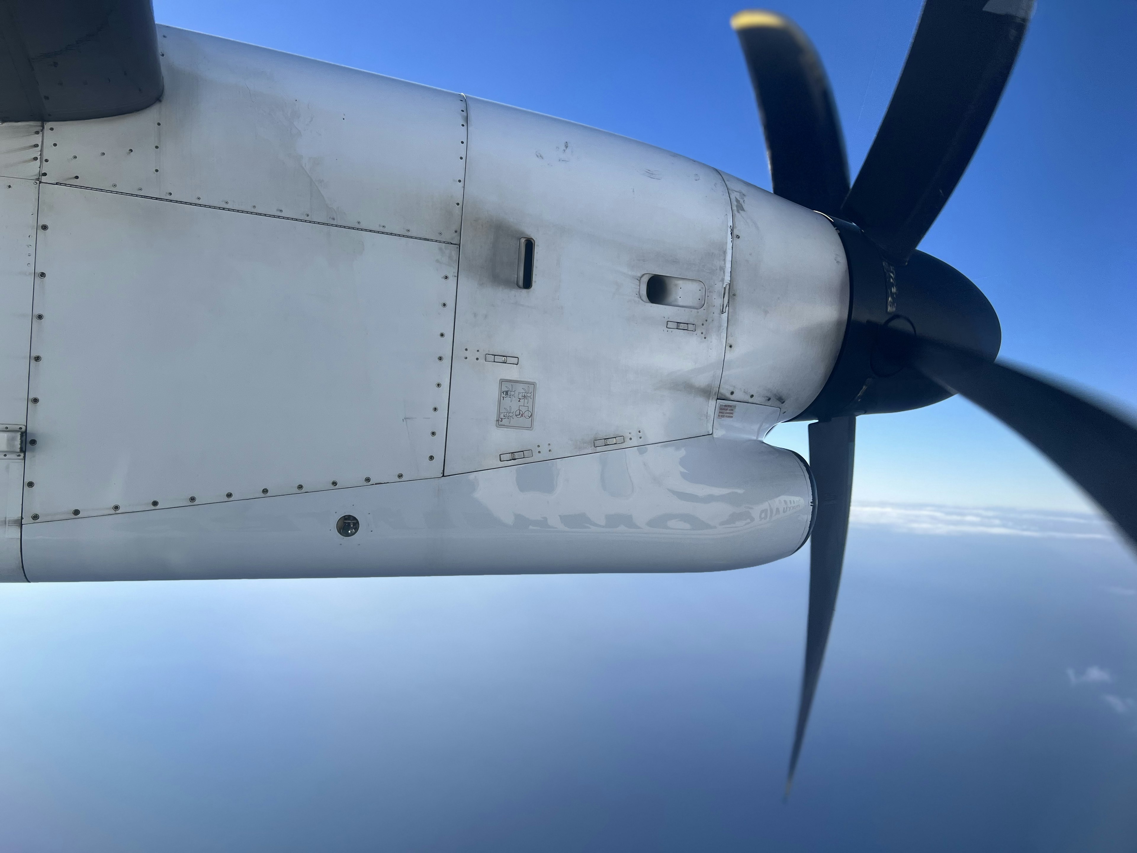 Bild eines Flugzeugpropellers und eines Flügels vor einem blauen Himmel