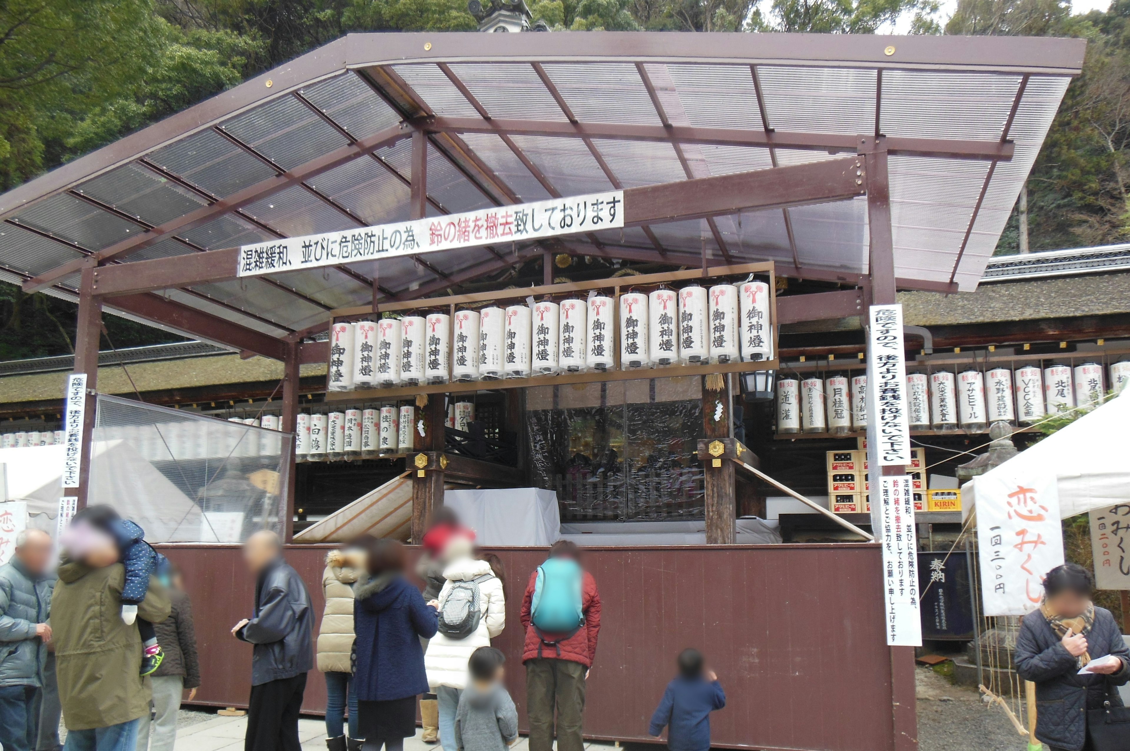 Roofed structure at a shrine entrance featuring numerous lanterns and people