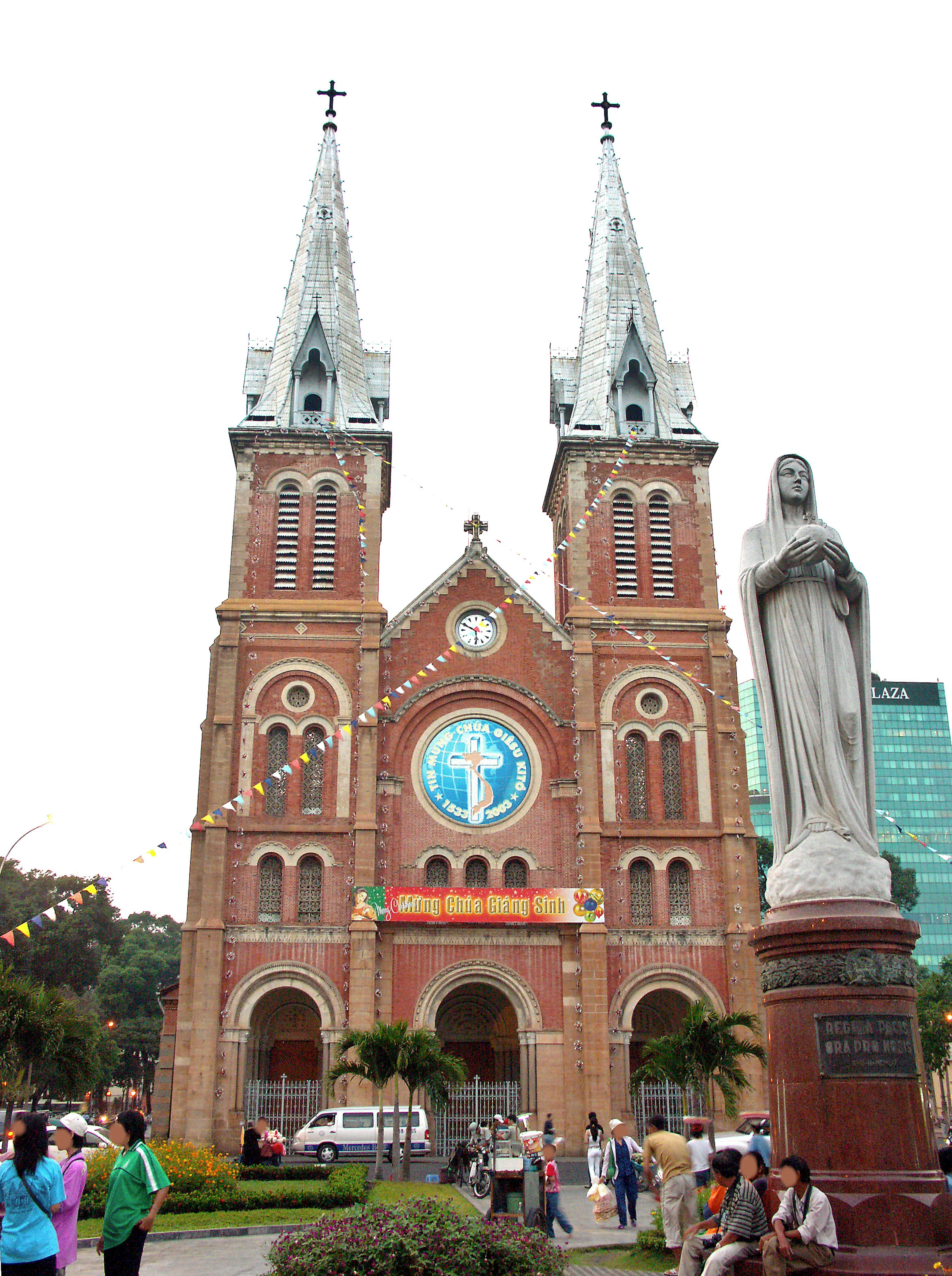 Red brick church with twin spires and a statue of the Virgin Mary in front