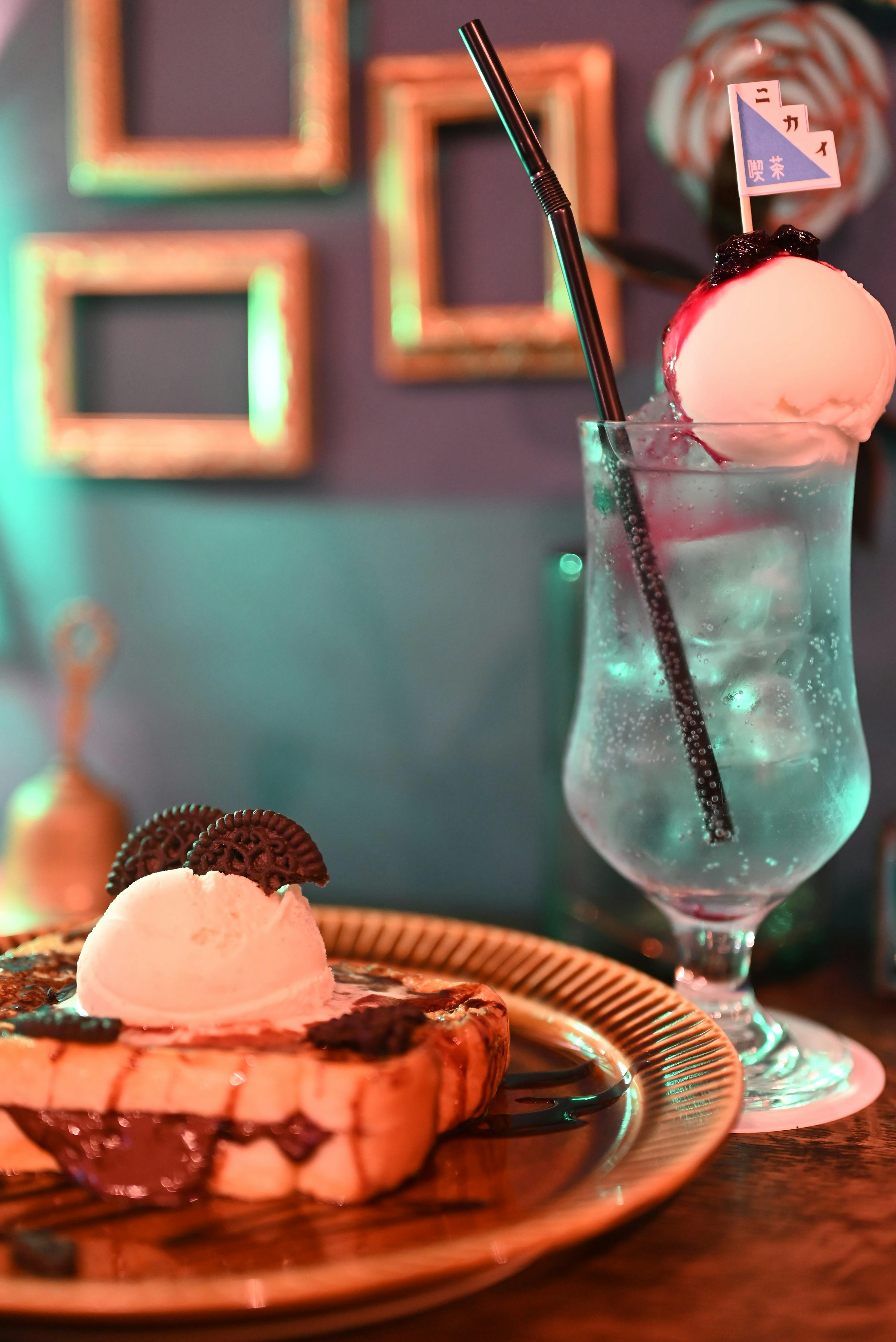 Dessert featuring toast topped with ice cream and chocolate sauce alongside a blue cocktail in a glass