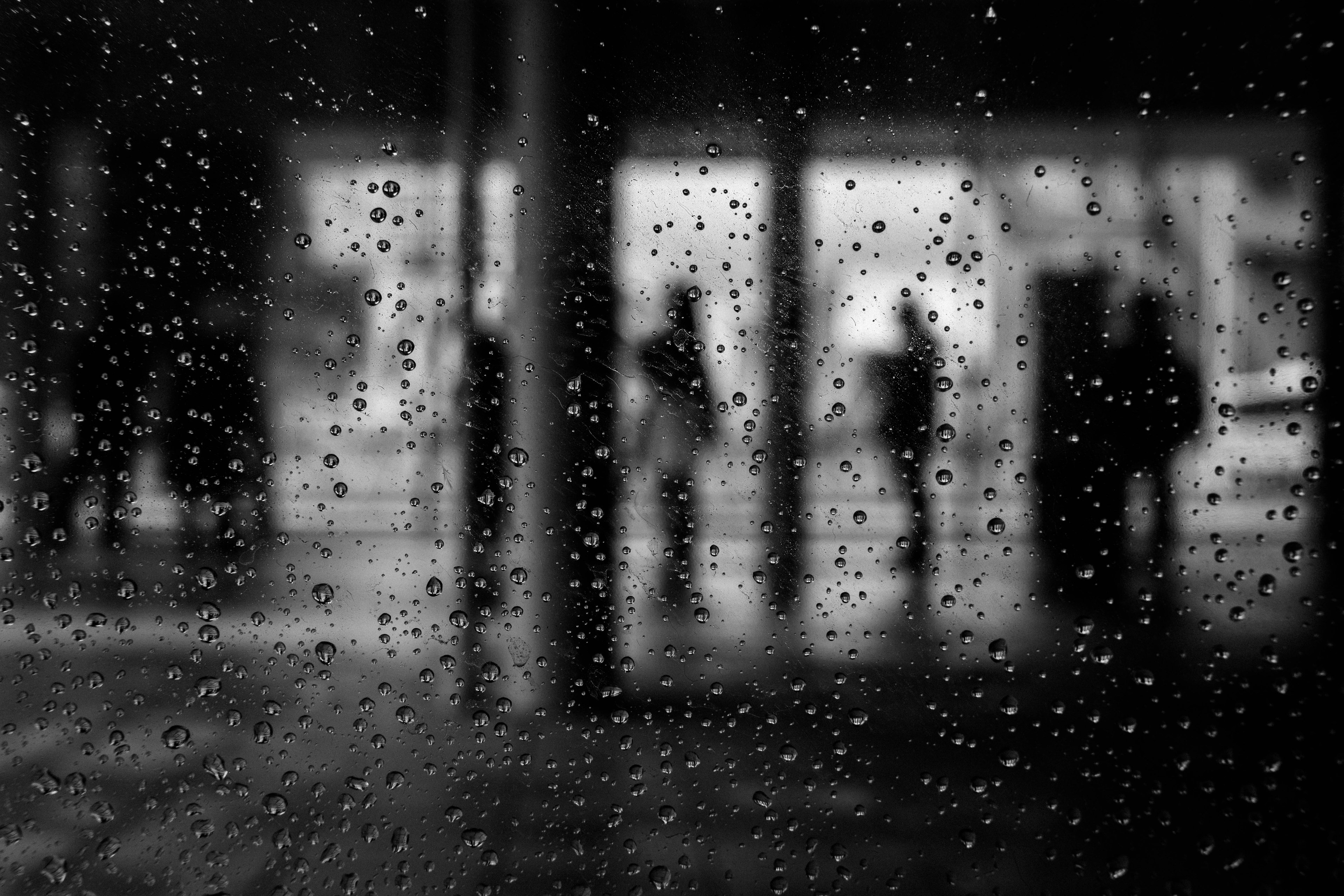 Silhouettes of people seen through a rain-specked window