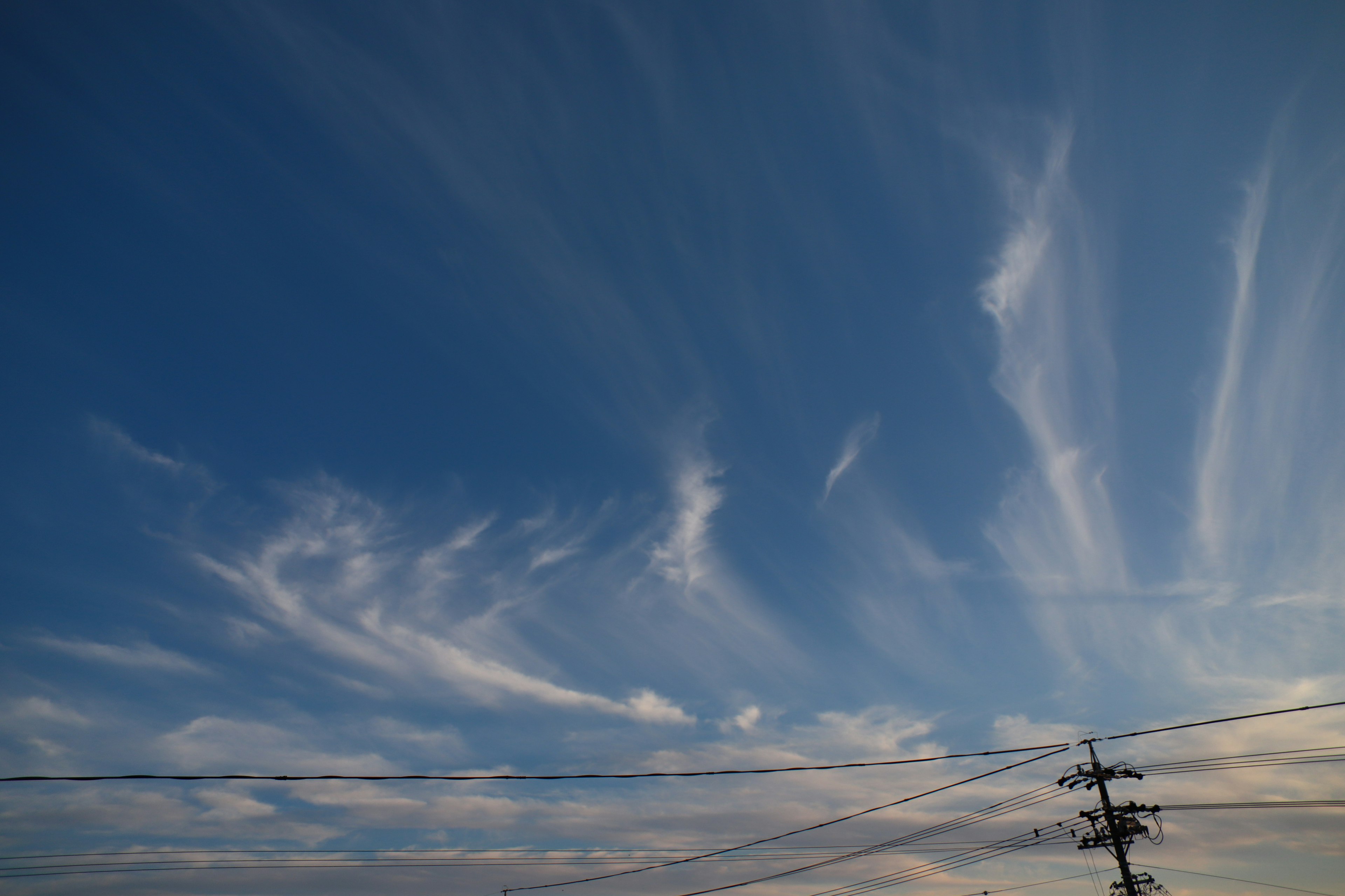 Cloud patterns in a blue sky with power lines