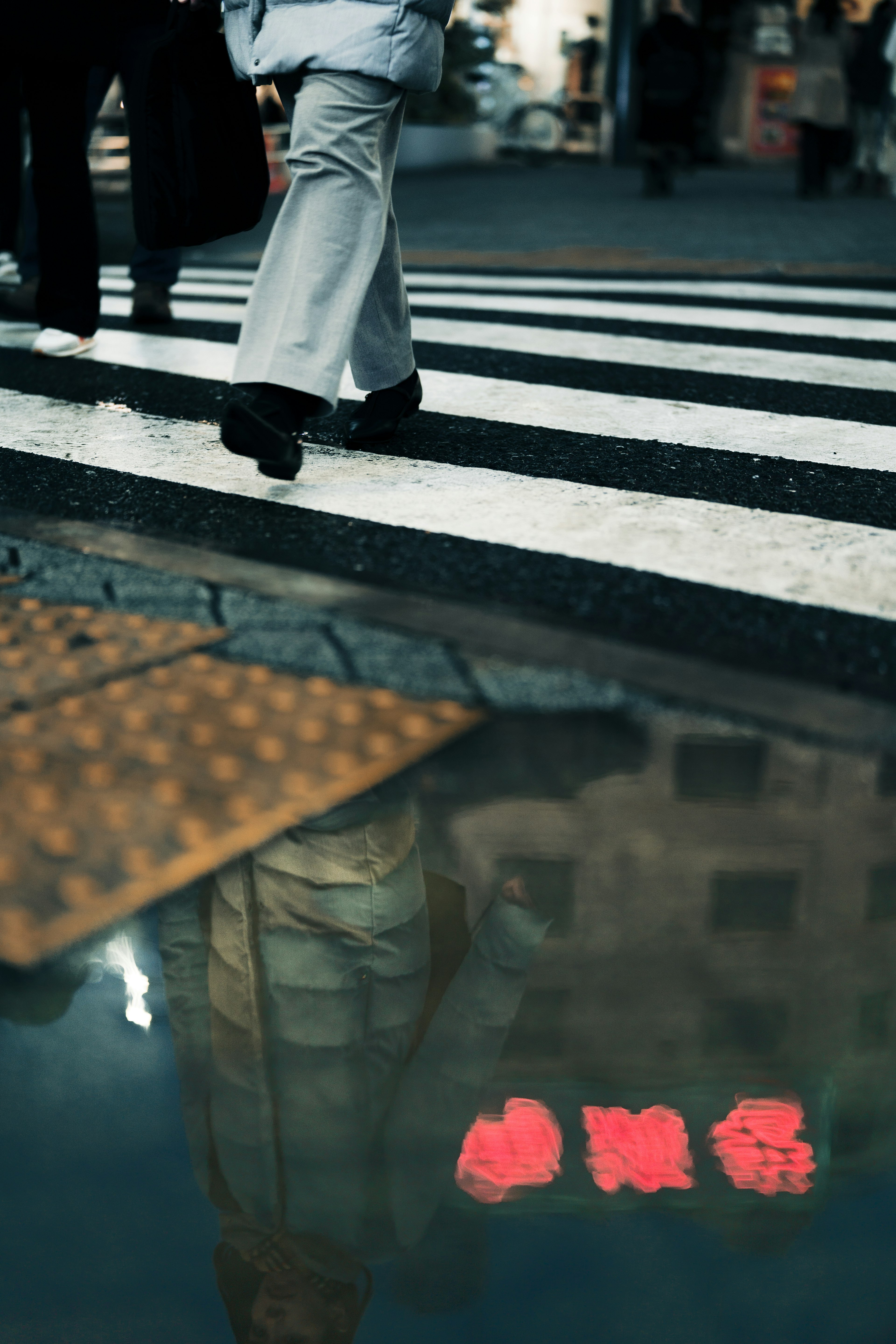 Reflection of red characters in a puddle beneath a pedestrian crossing