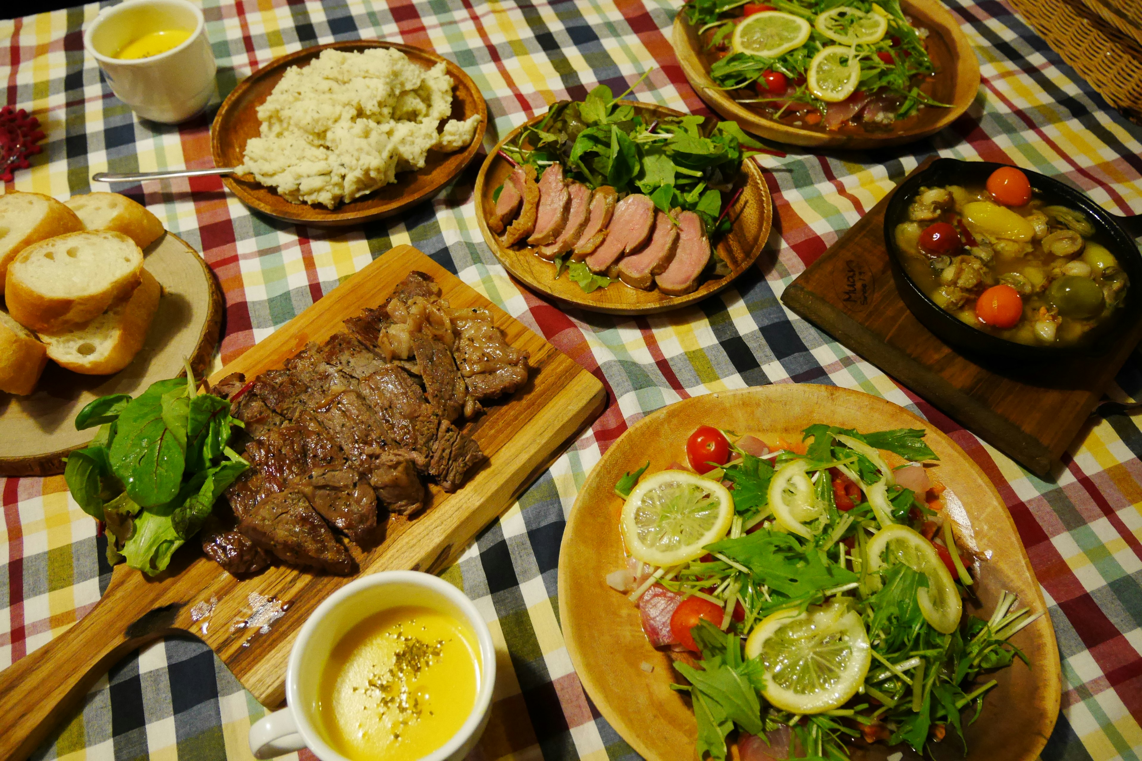 Una hermosa disposición de platos en una mesa con platos de carne ensalada y platos de arroz cubiertos con verduras frescas y limón