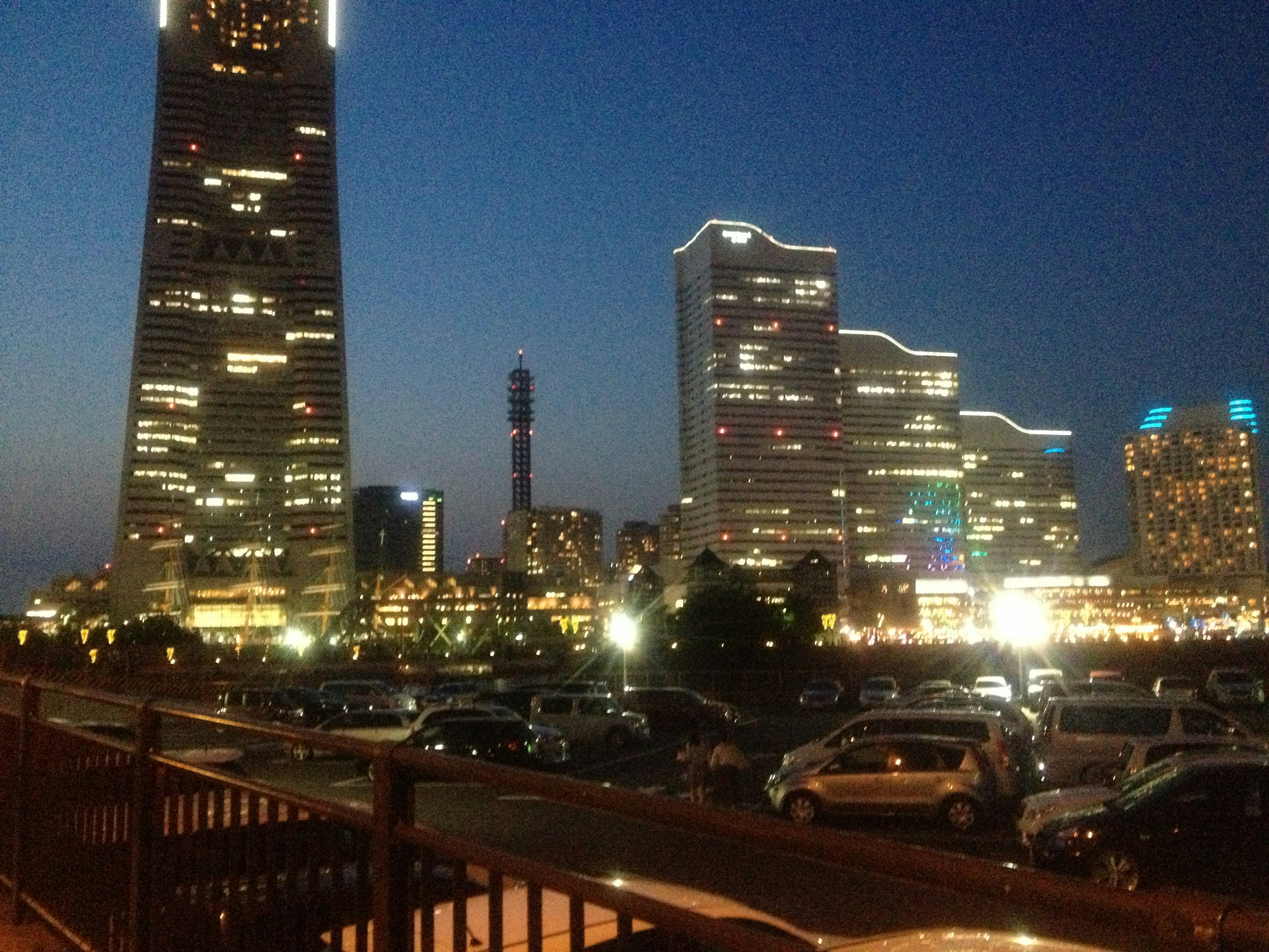 Vista nocturna de Yokohama con rascacielos y coches estacionados