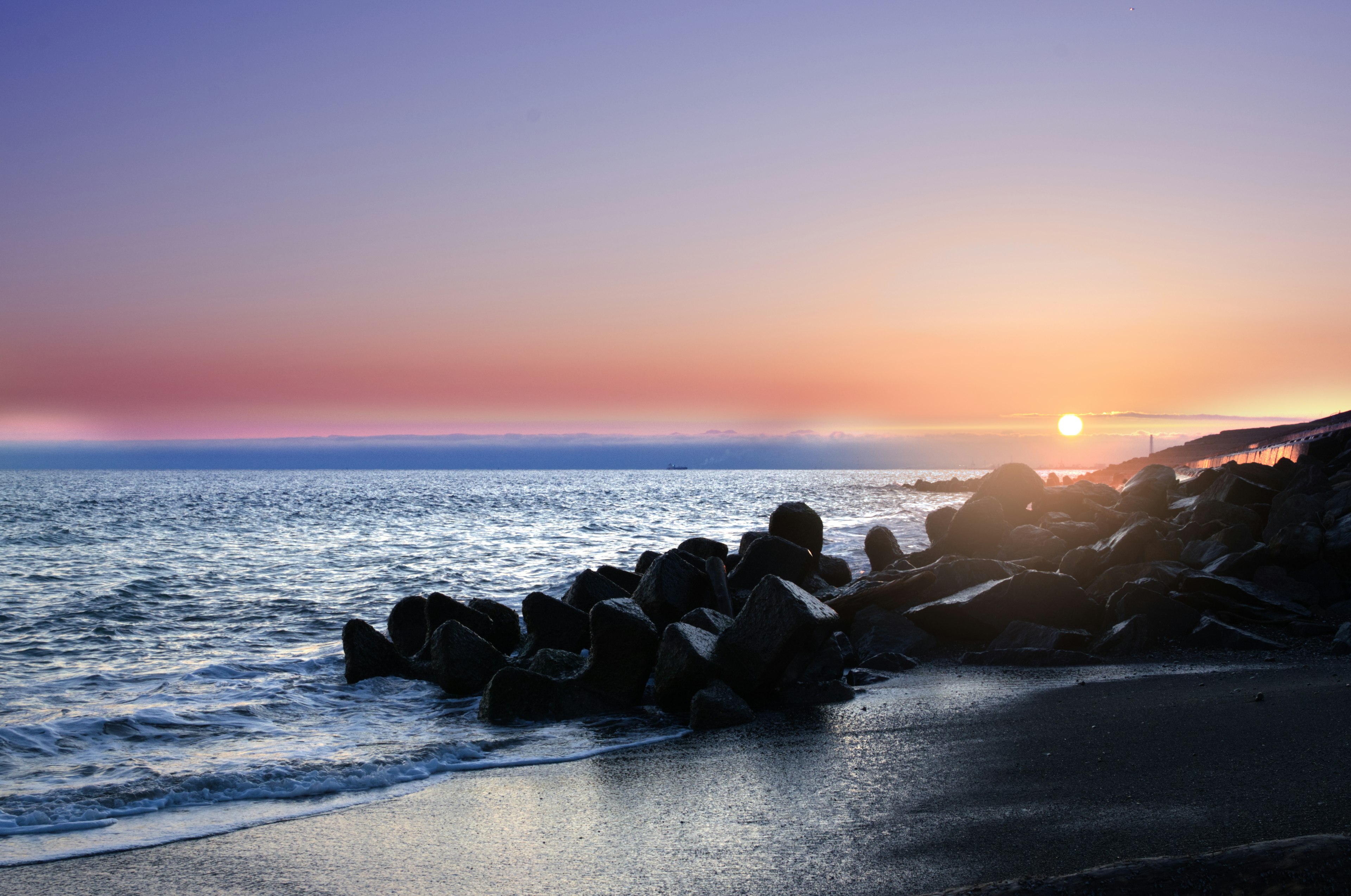 Scène de plage sereine au coucher du soleil avec des rochers le long du rivage