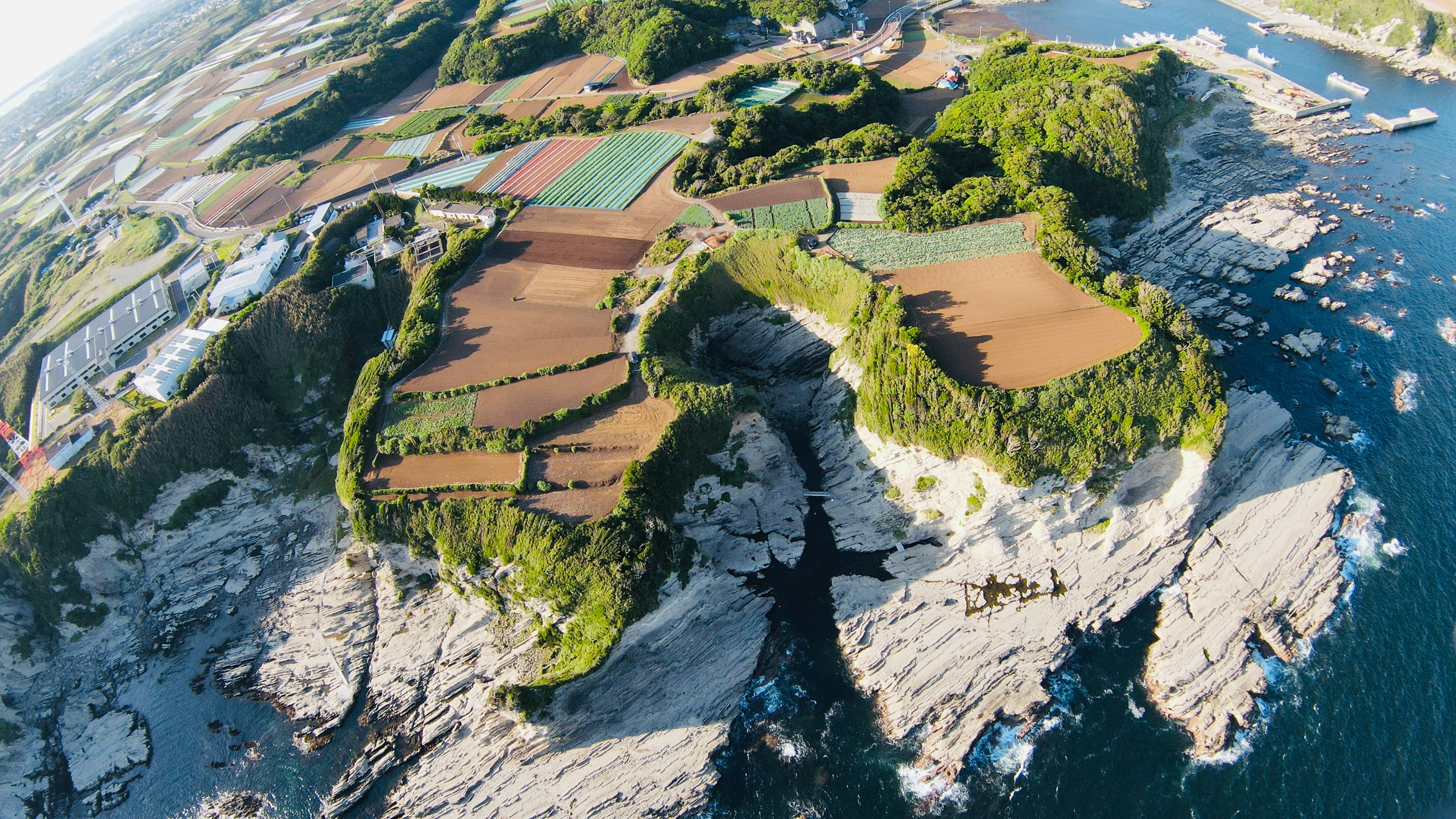 Vista aérea de tierras agrícolas exuberantes rodeadas por un océano azul y una costa rocosa