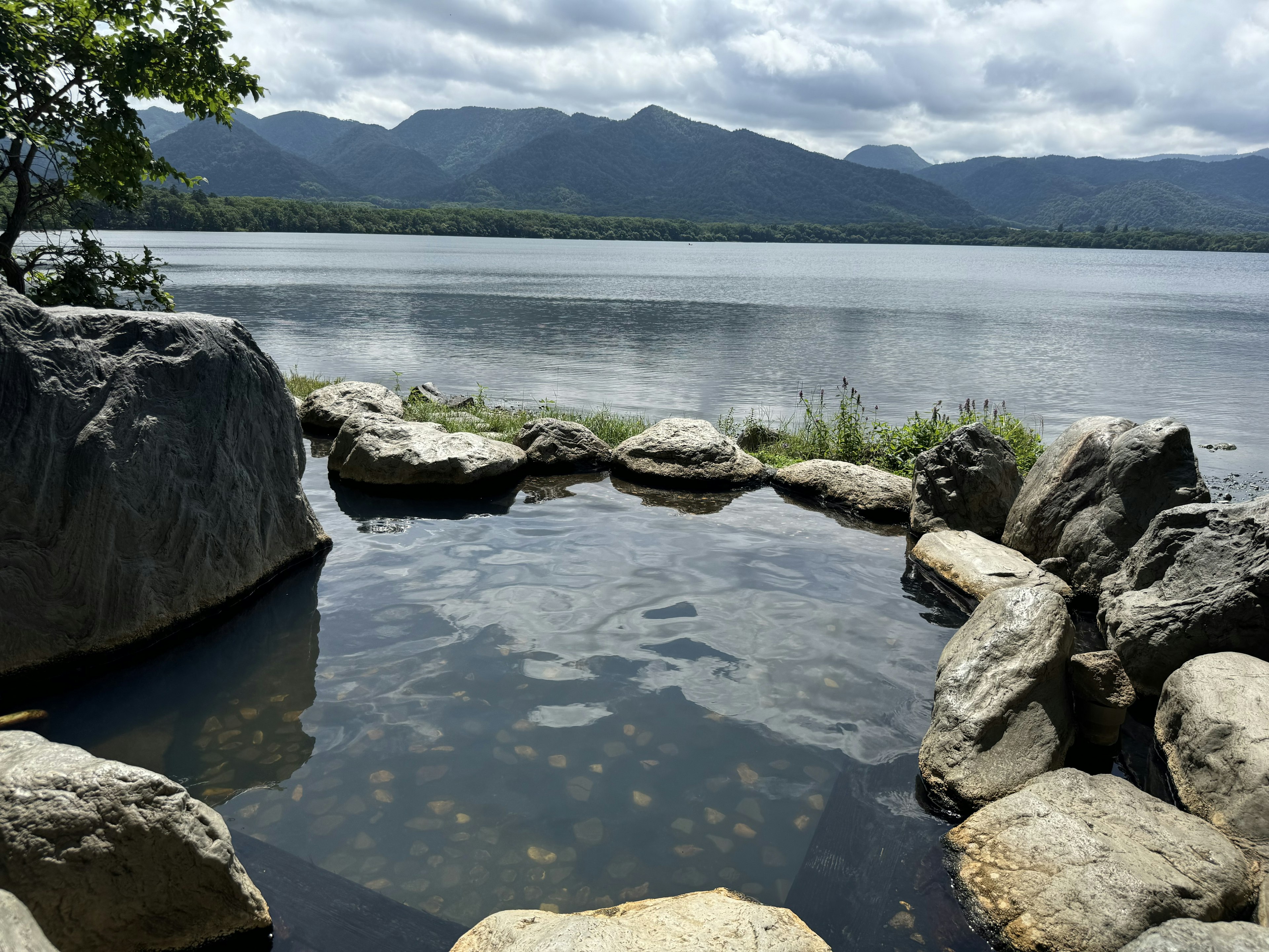 Natural hot spring by a tranquil lake surrounded by rocks