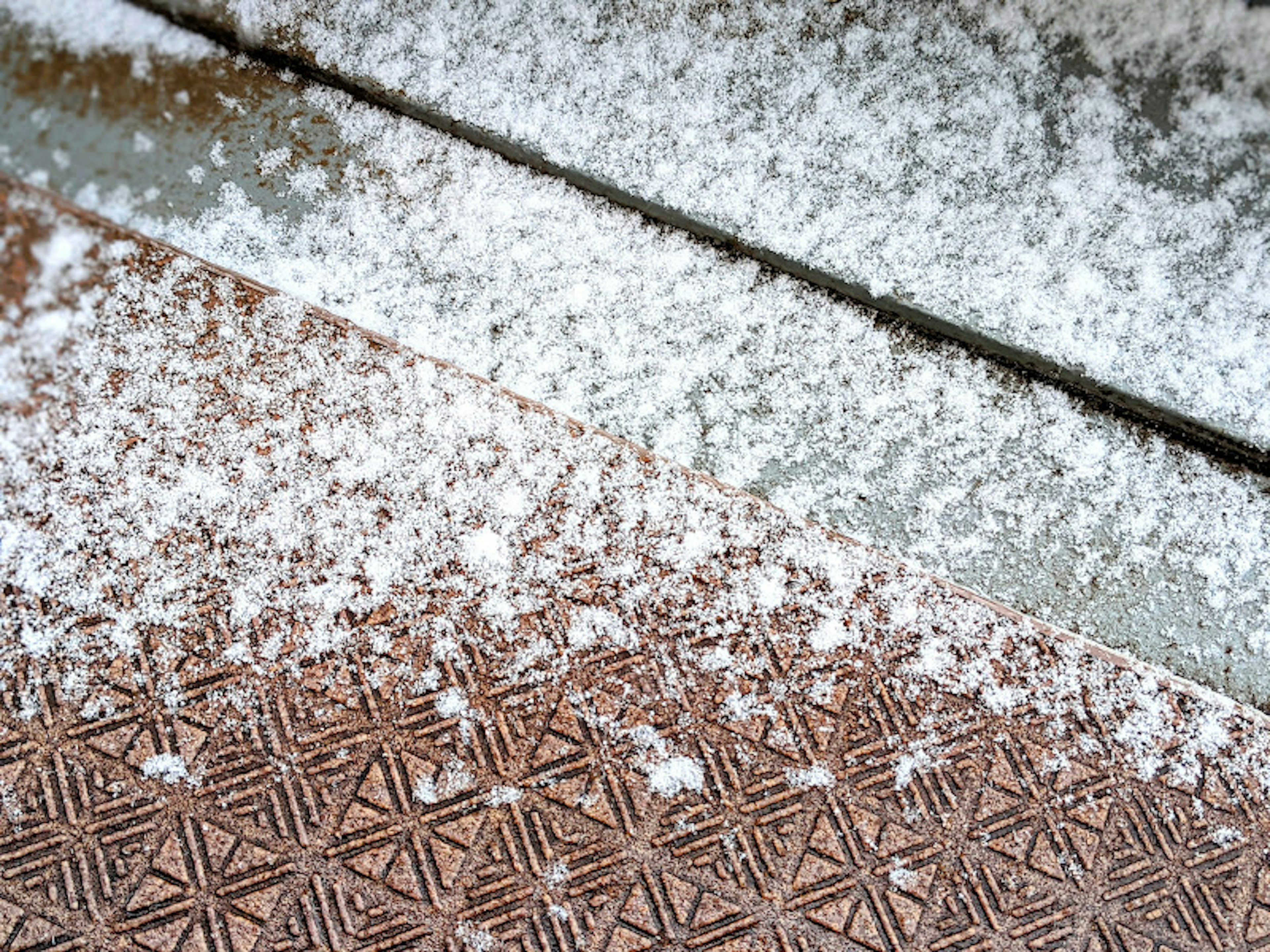 Close-up of a door mat with scattered snowflakes