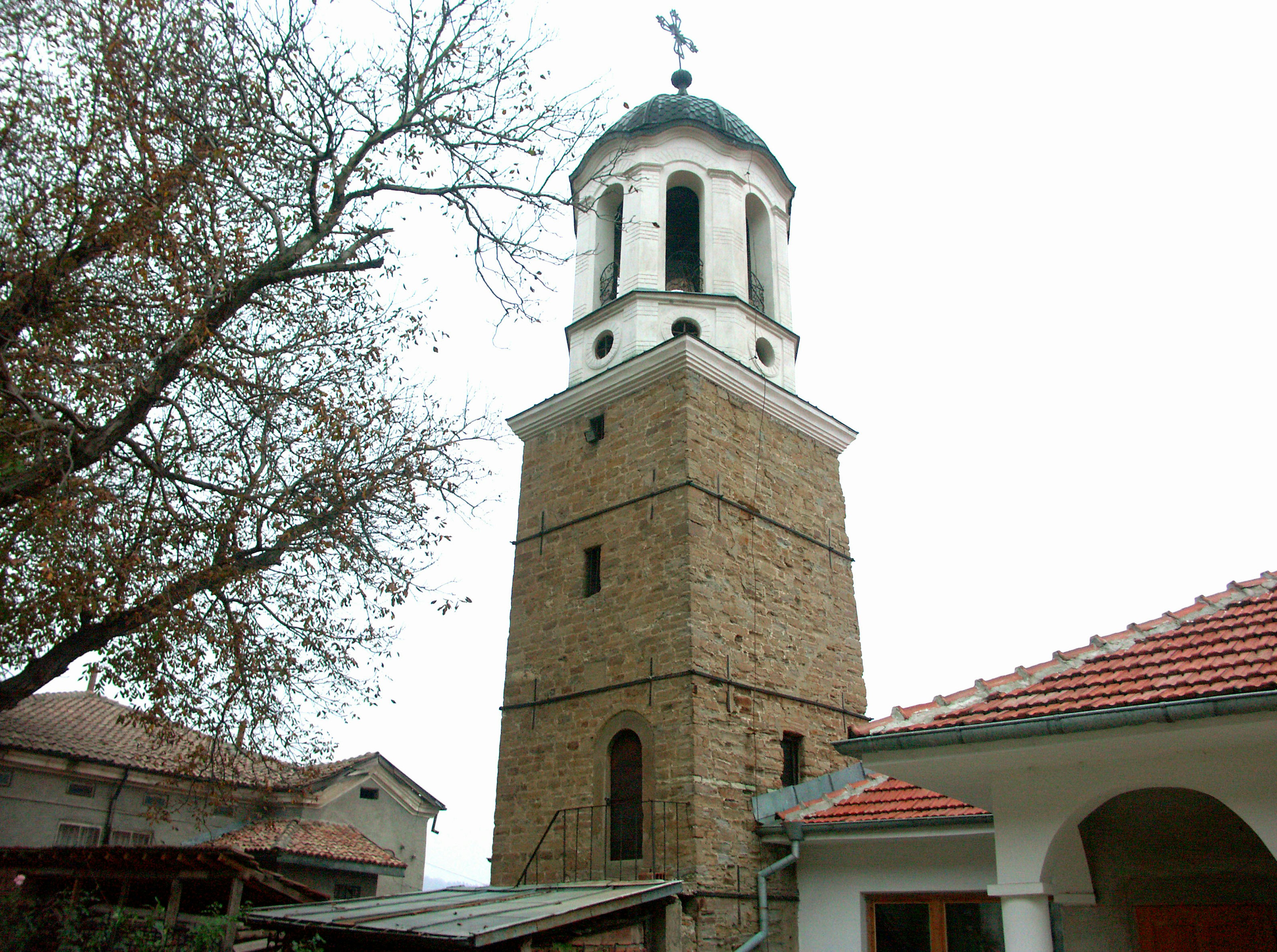 A historic stone bell tower with a dome and cross