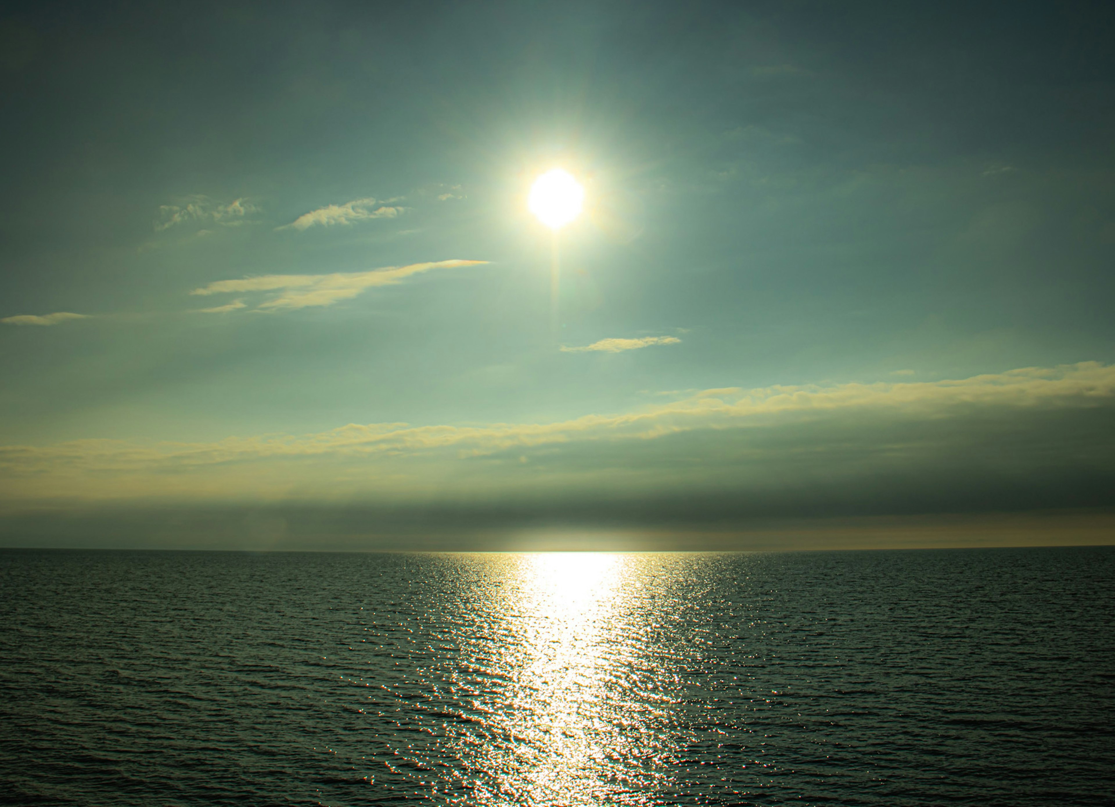 太陽が水面に反射する静かな海の風景