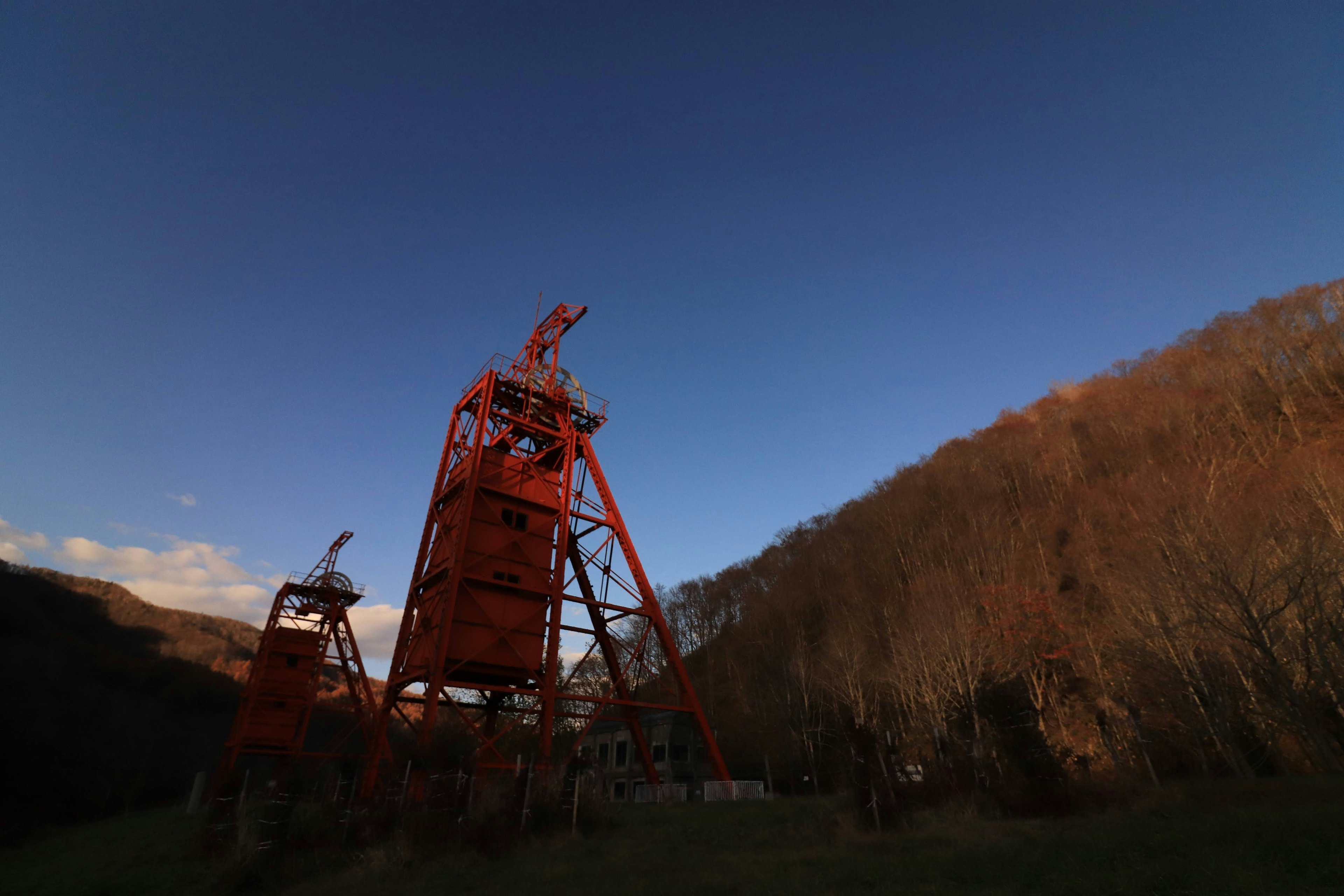 Orangefarbene Turmstruktur vor einer Berglandschaft bei Sonnenuntergang