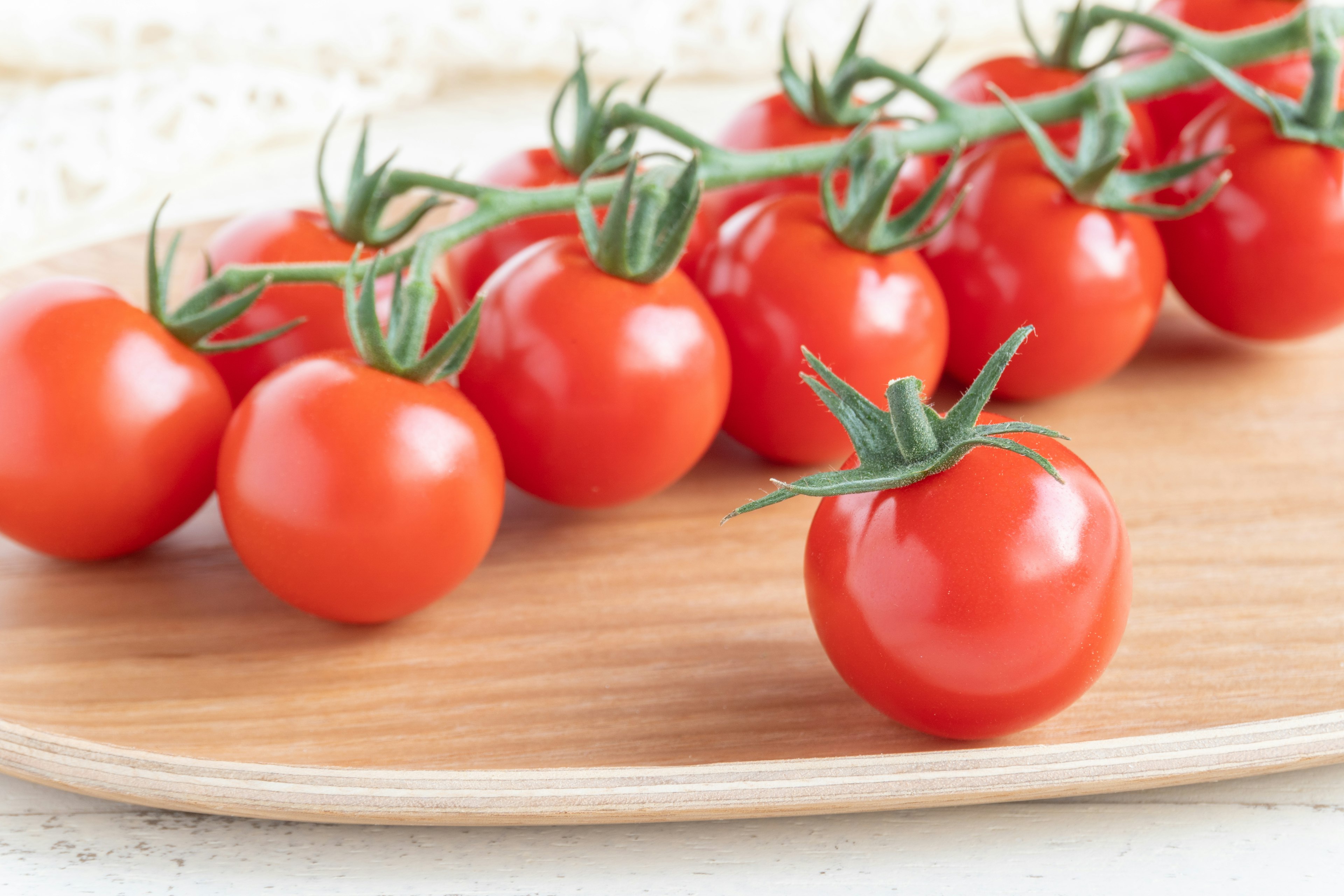 Fresh red mini tomatoes arranged on a wooden platter