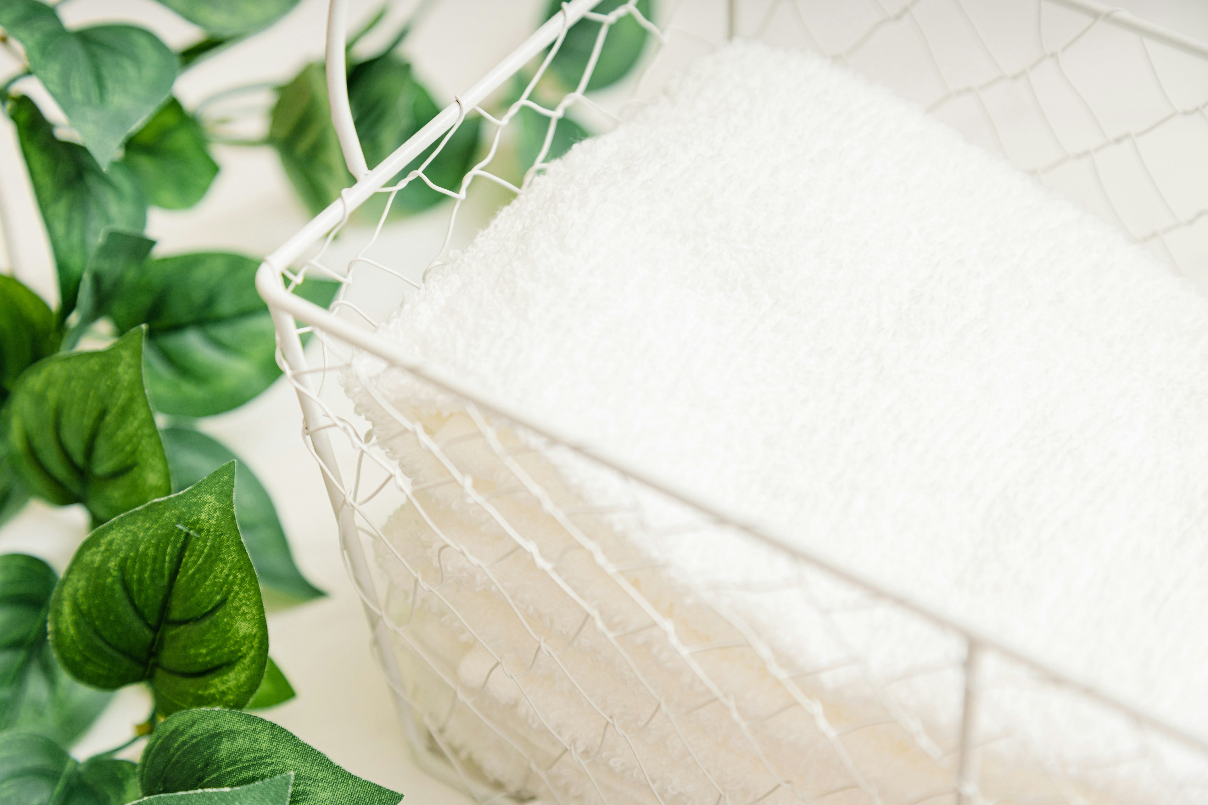 Serviette blanche douce dans un panier en fil avec des feuilles vertes