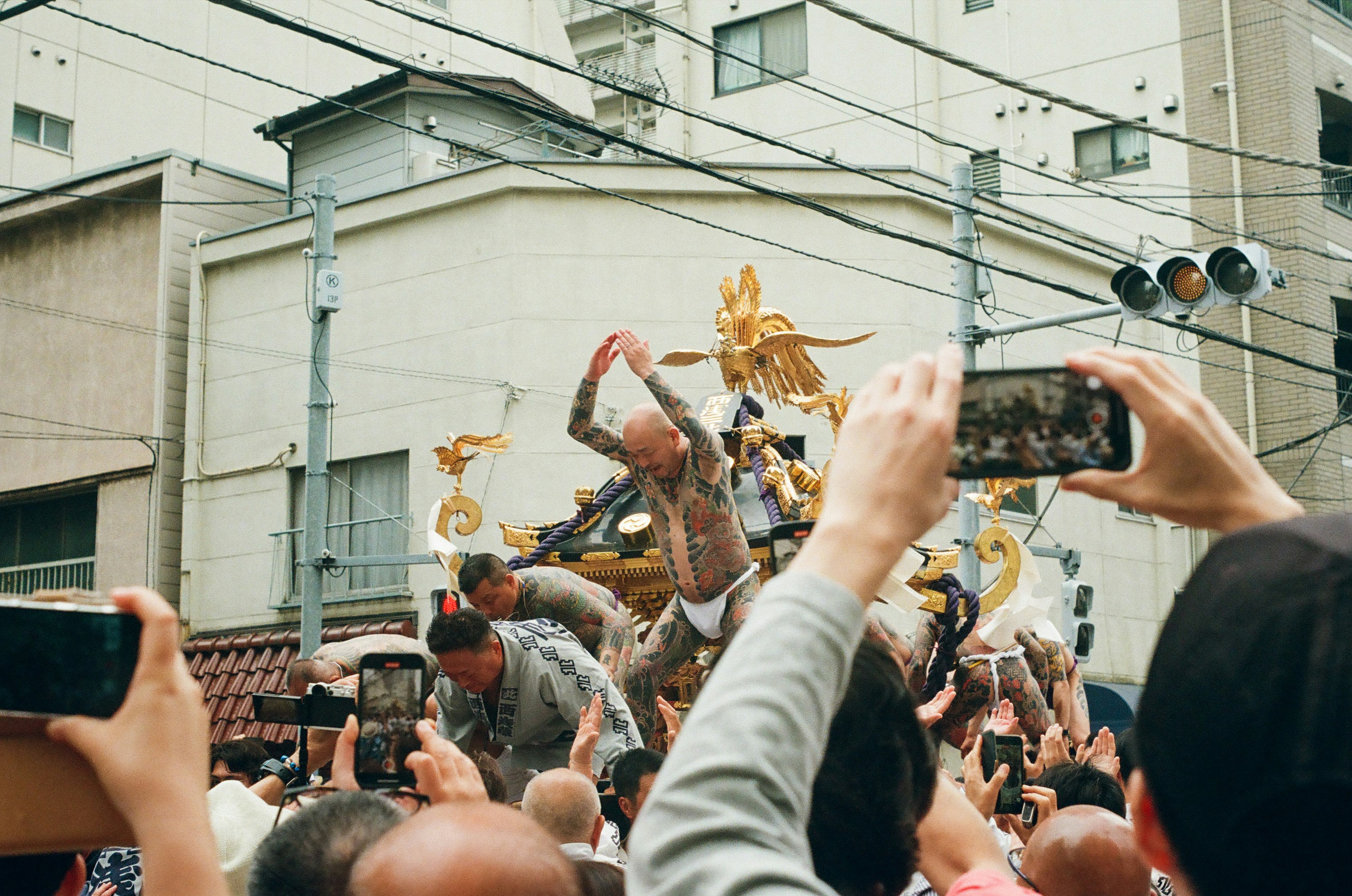 Participantes llevando un santuario portátil durante un festival personas alrededor tomando fotos con smartphones