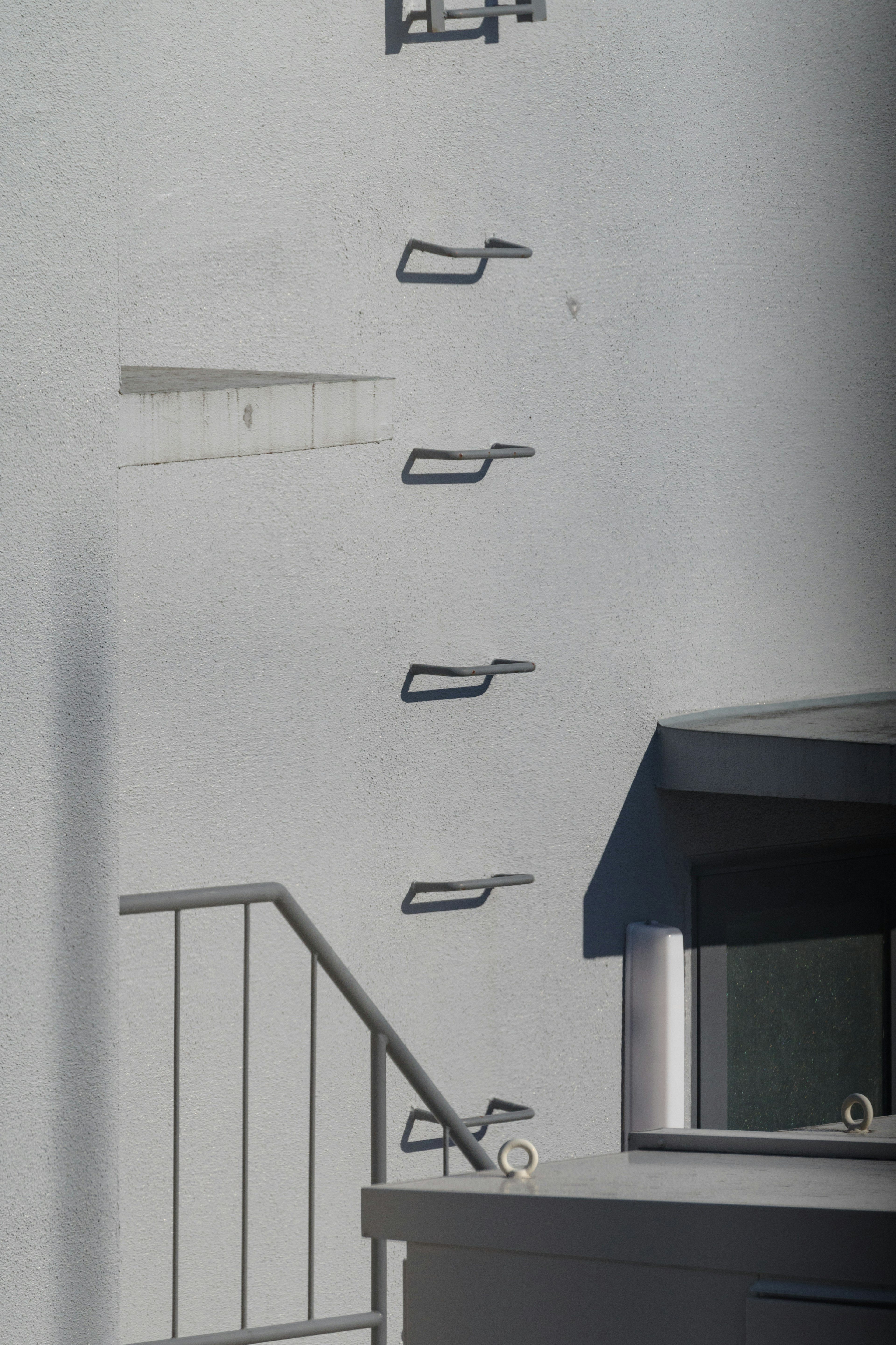 Garde-corps en métal montés sur un mur blanc avec un escalier visible