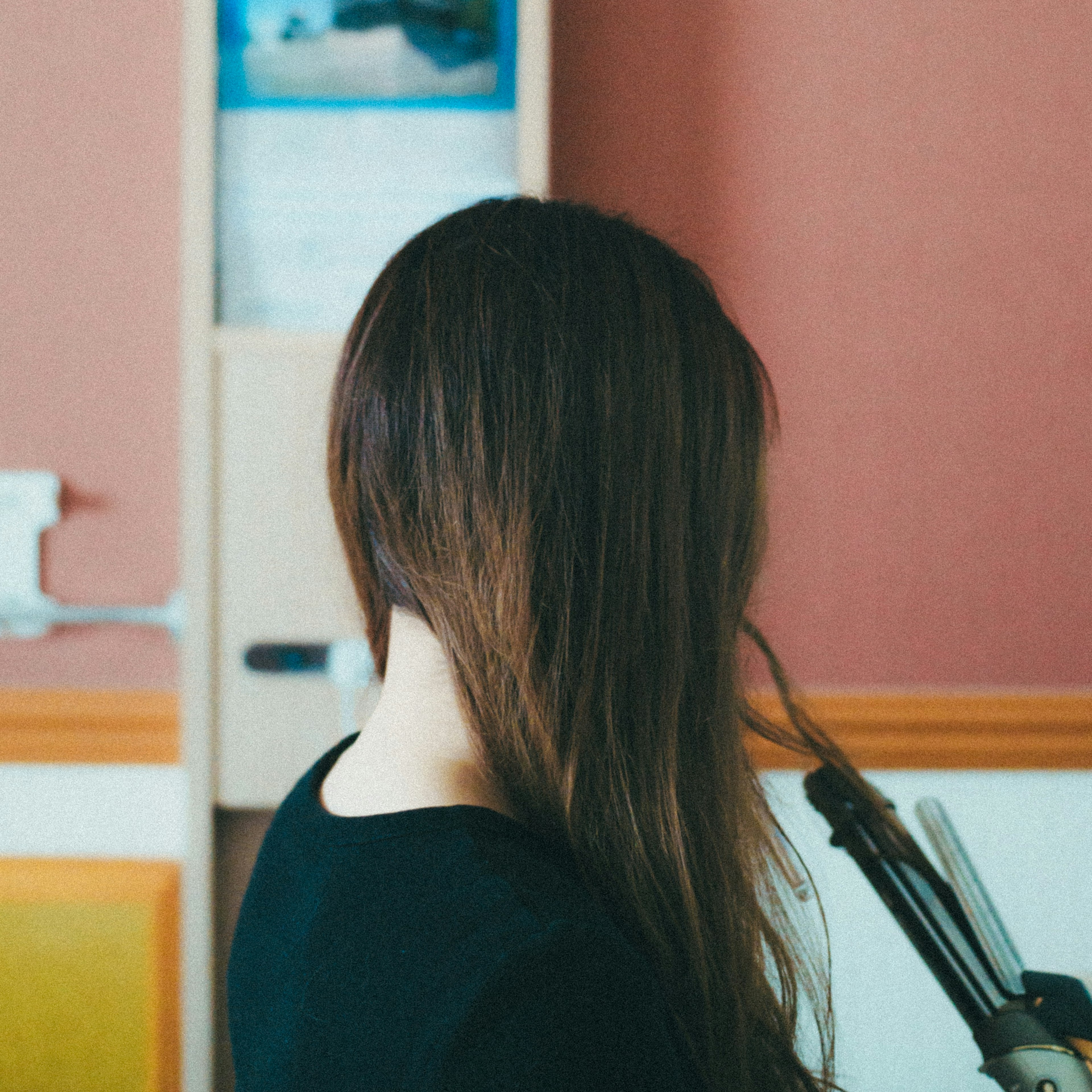 Femme utilisant un lisseur à cheveux vue de dos dans un cadre intérieur