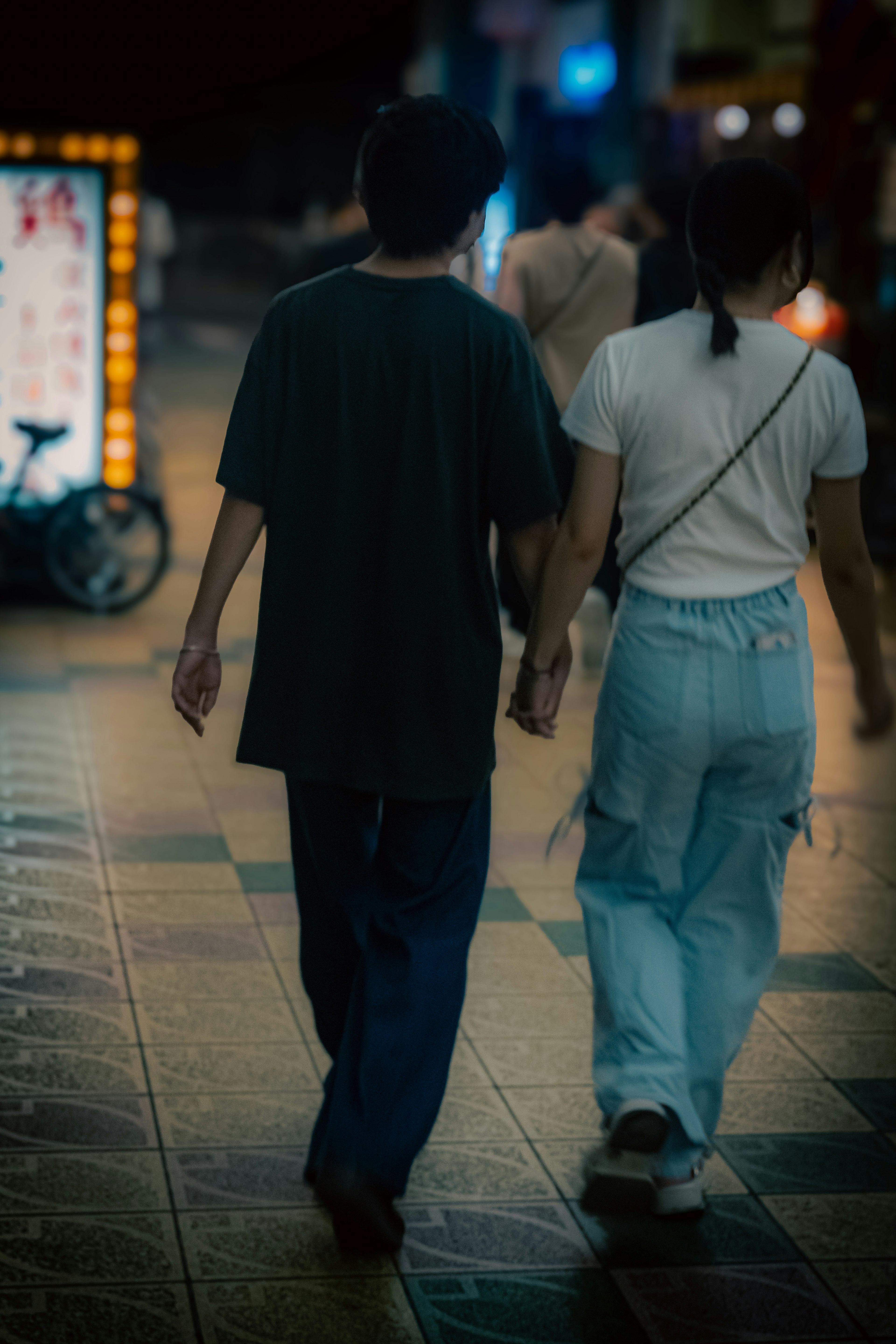 Un couple marchant main dans la main dans un cadre urbain nocturne