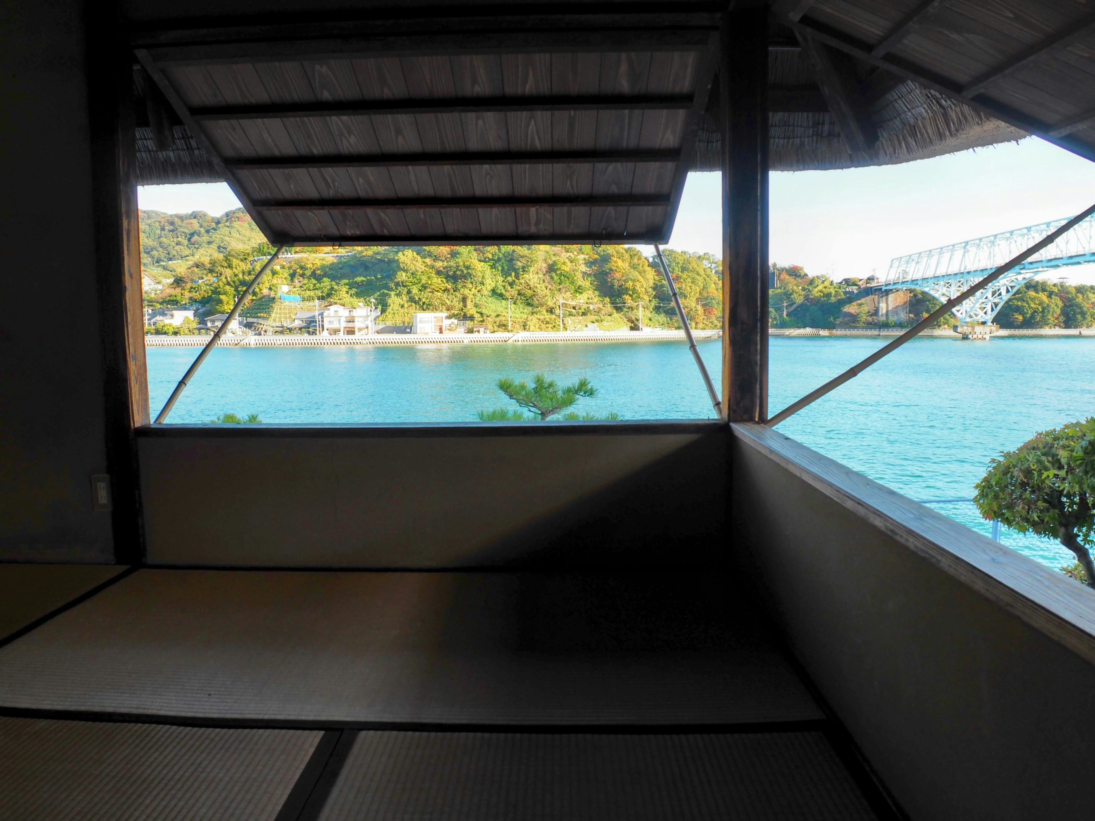 Interior ruangan Jepang dengan pemandangan laut tenang dan gunung hijau