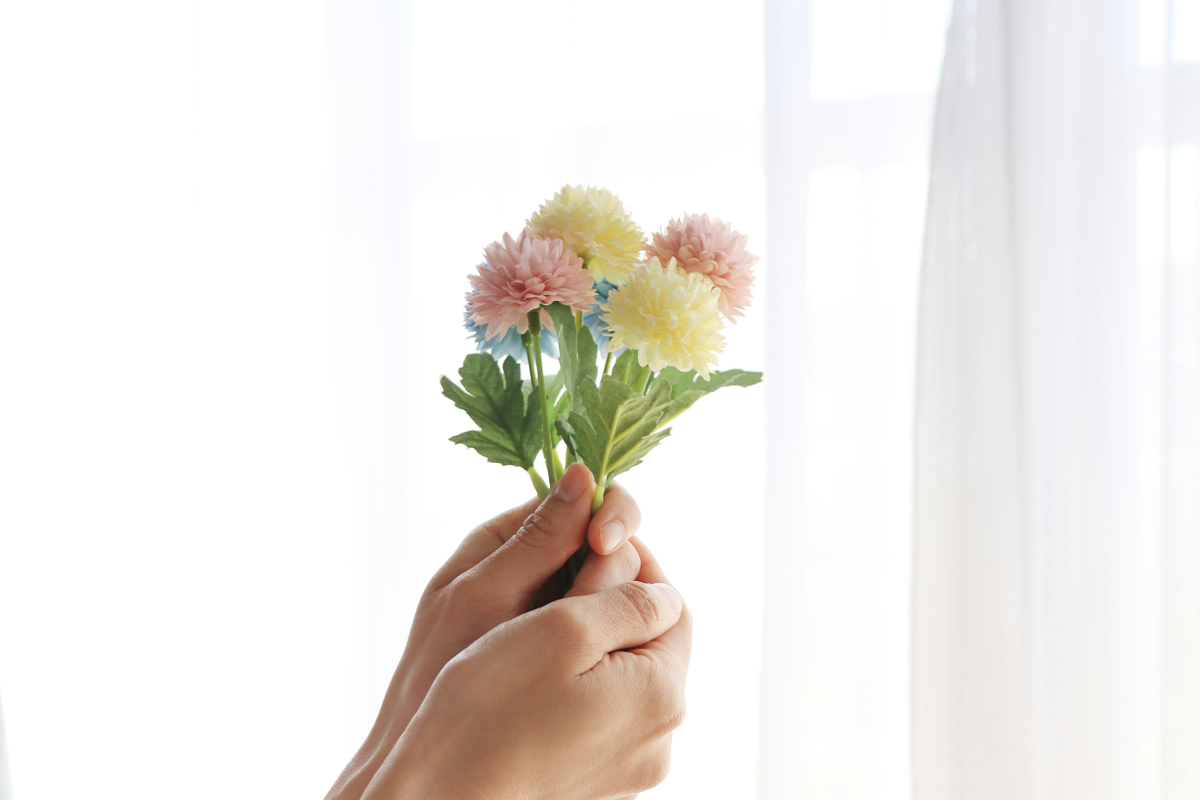 Hands holding a soft-colored bouquet of flowers