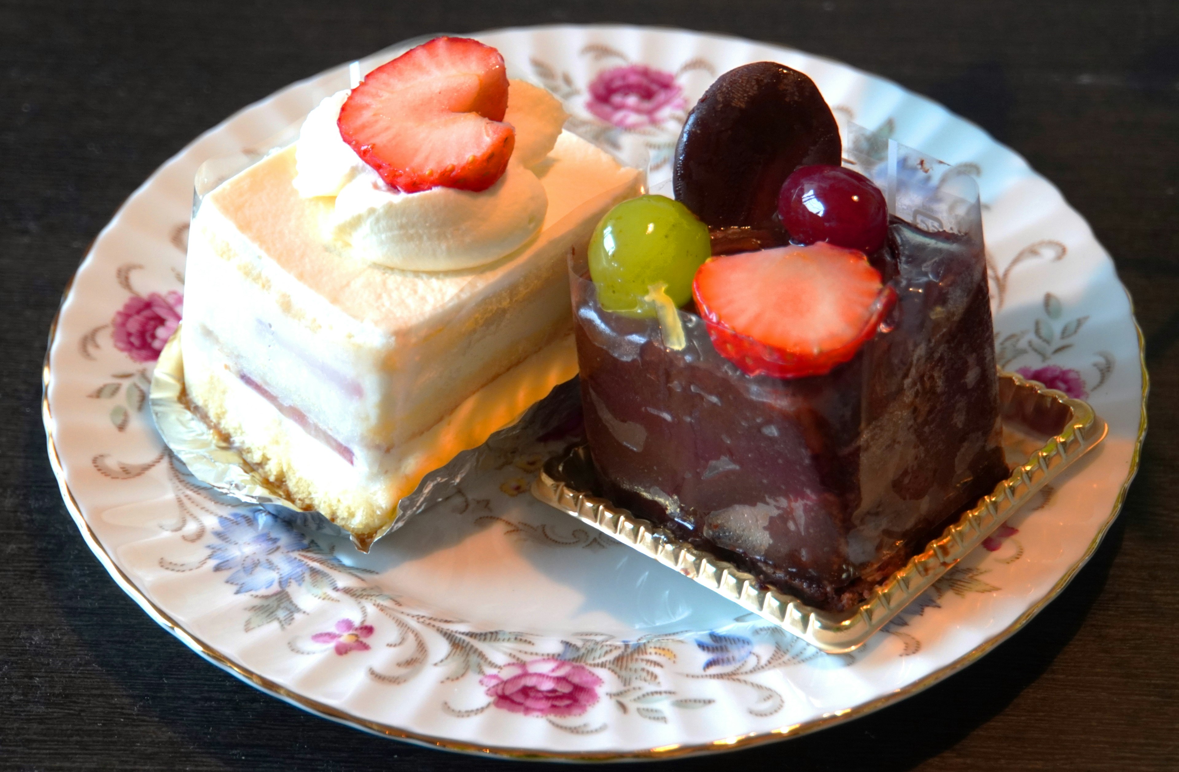 Piring cantik dengan kue putih dan kue coklat dihias buah