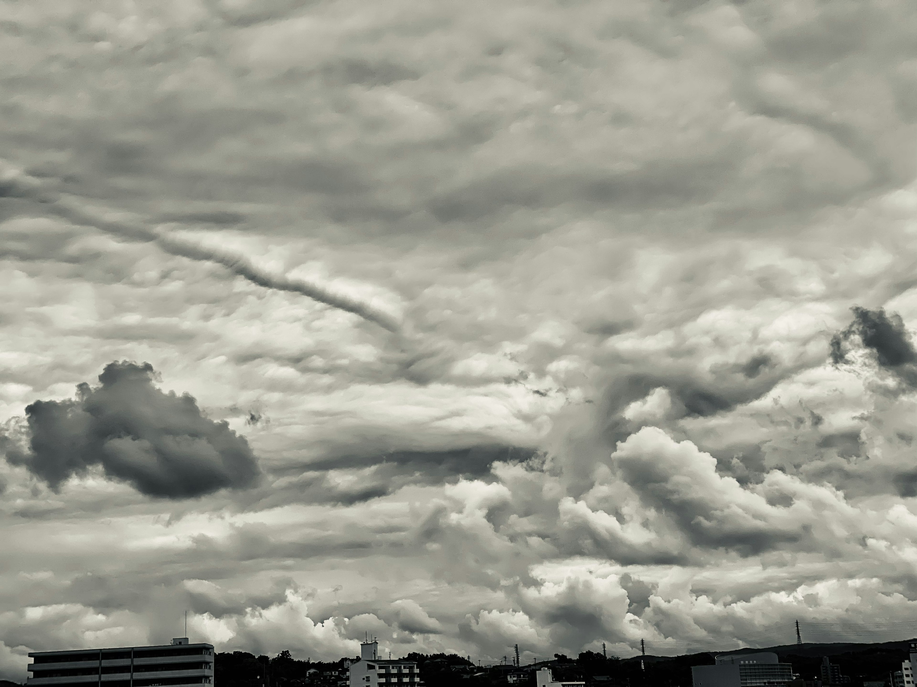 Ciel gris rempli de nuages et silhouettes de bâtiments